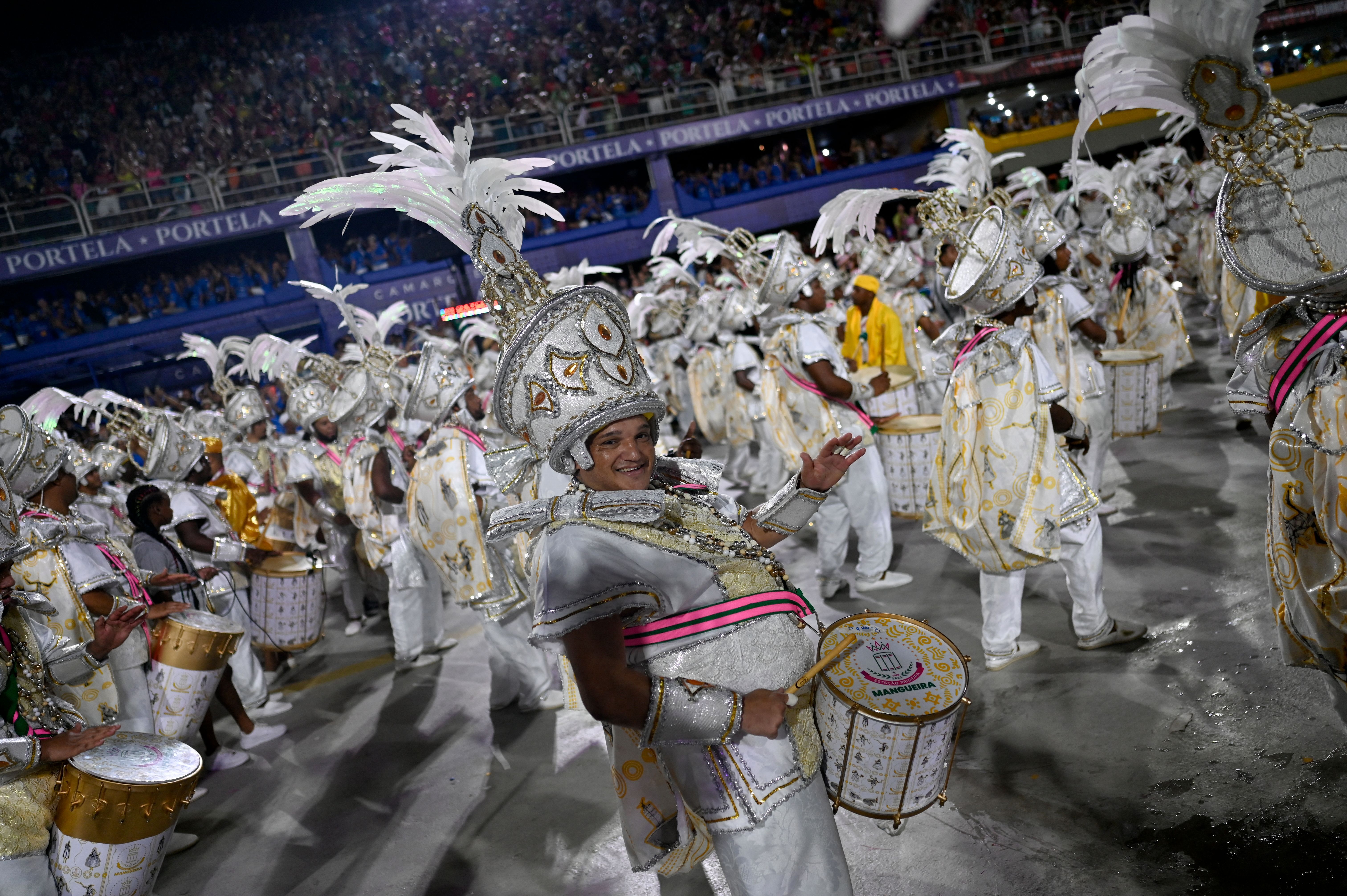 A drumline in shiny and encrusted white outfits play their drums during Carnival in Brazil