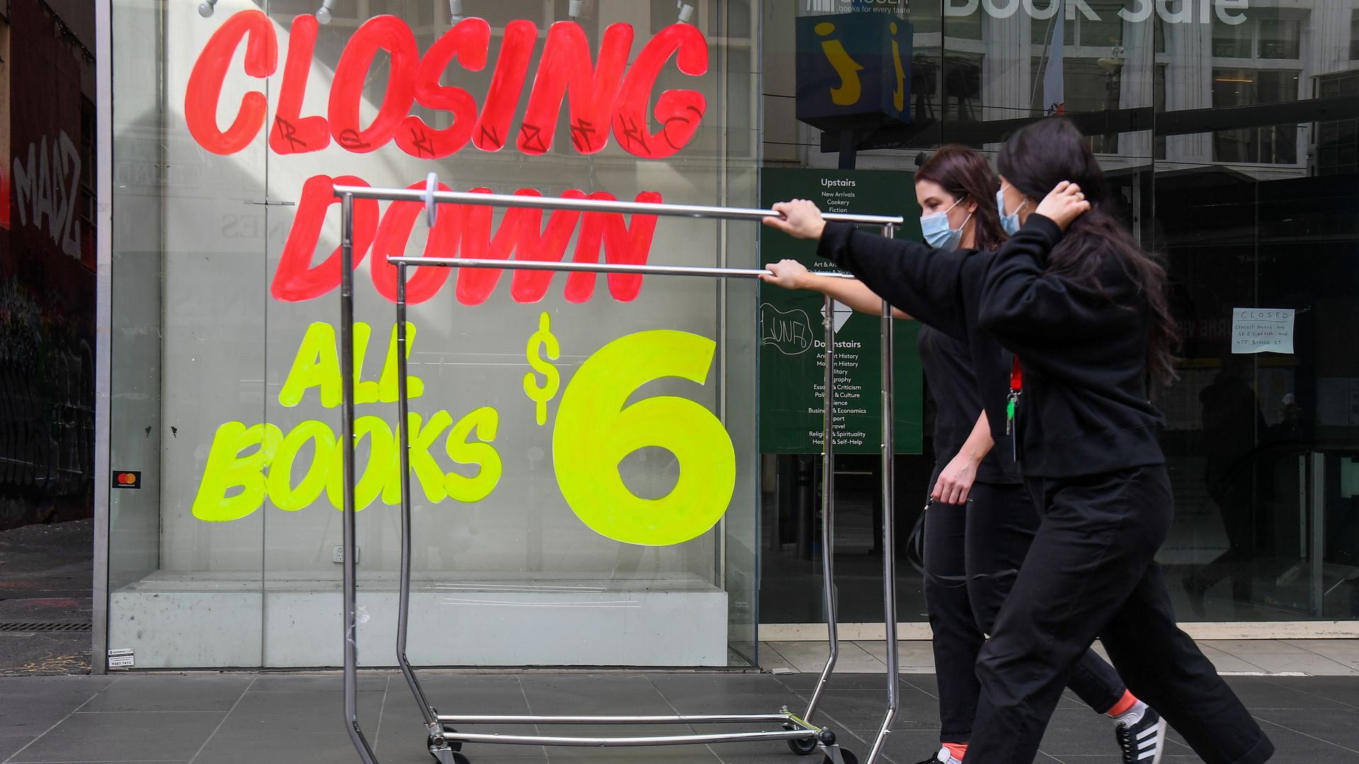 Workers push trolleys past an empty shop in Melbournes central business district on August 3
