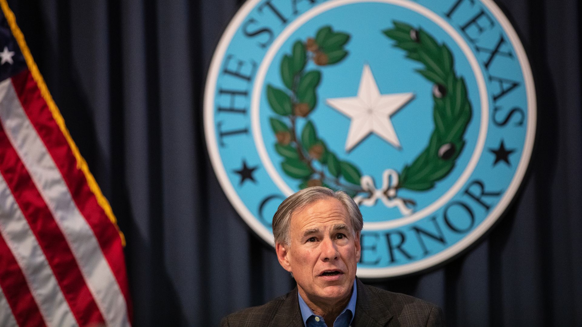 Photo of Greg Abbott's head against a background with the Texas state seal