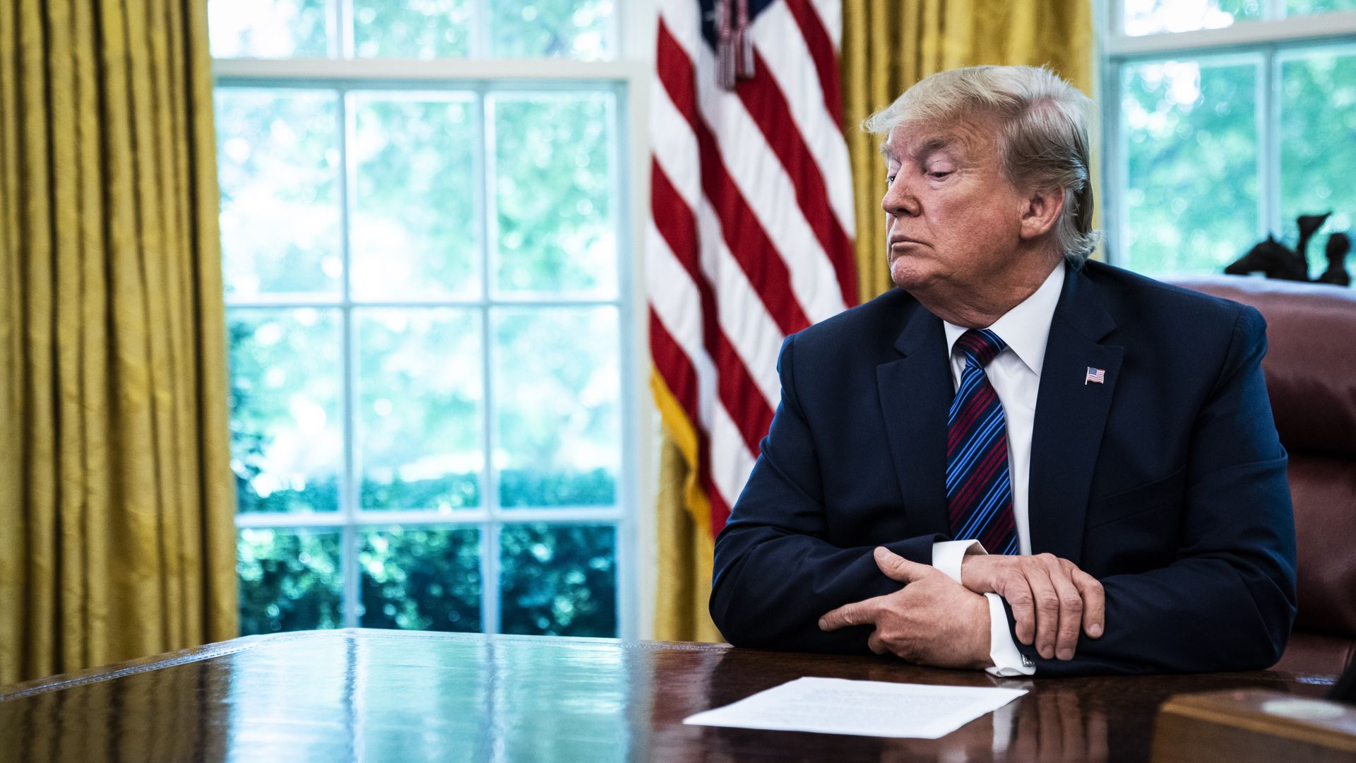 Photo of President Trump sitting at his desk with an agreement in front of him
