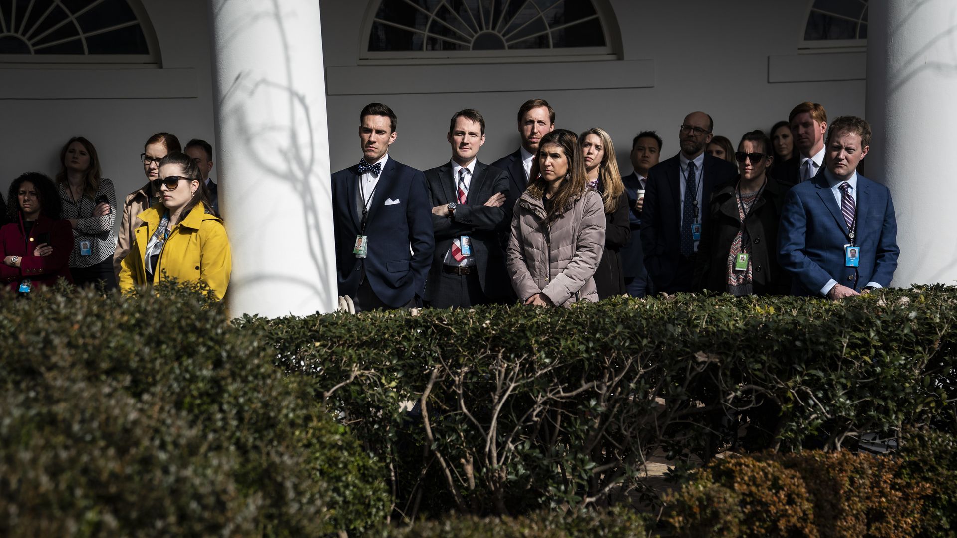 White House staff members watch as the president delivers a speech in the Rose Garden. 