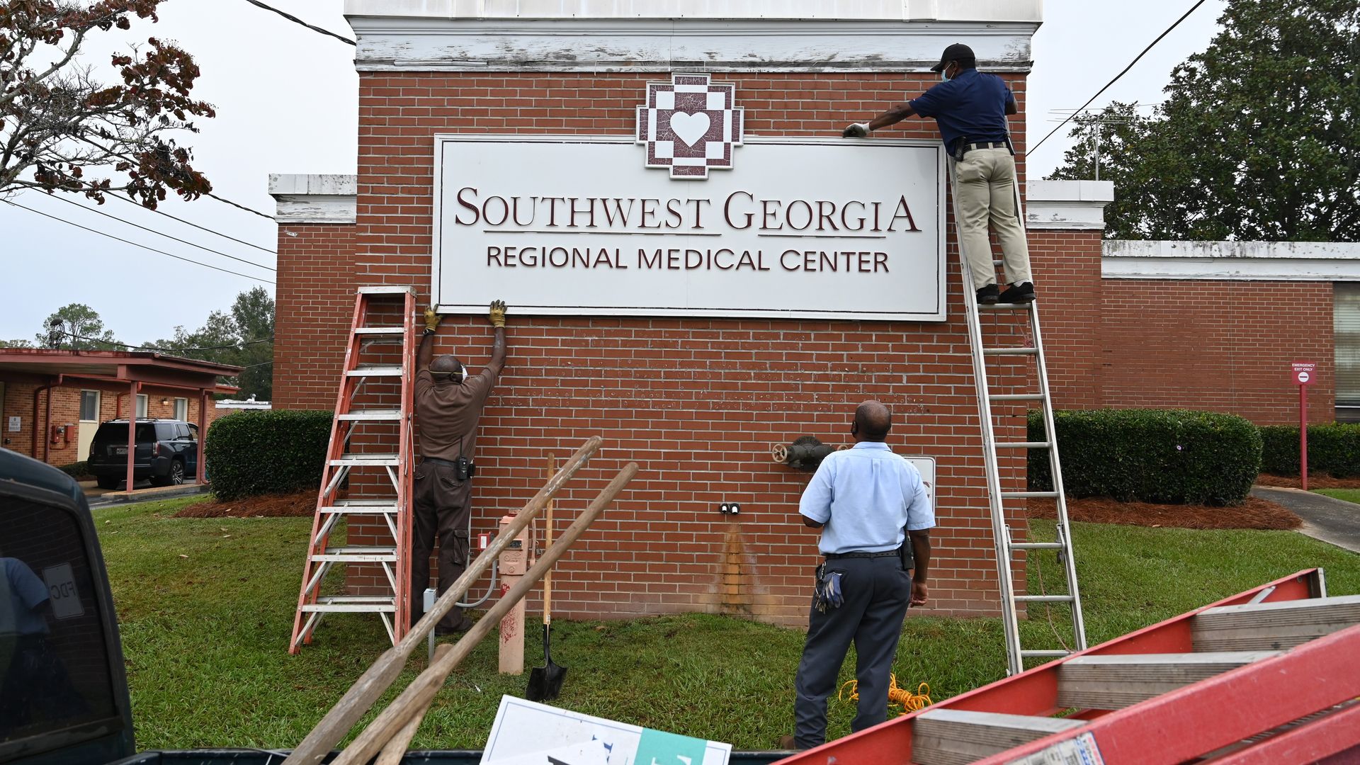 Men on ladders take down a hospital sign