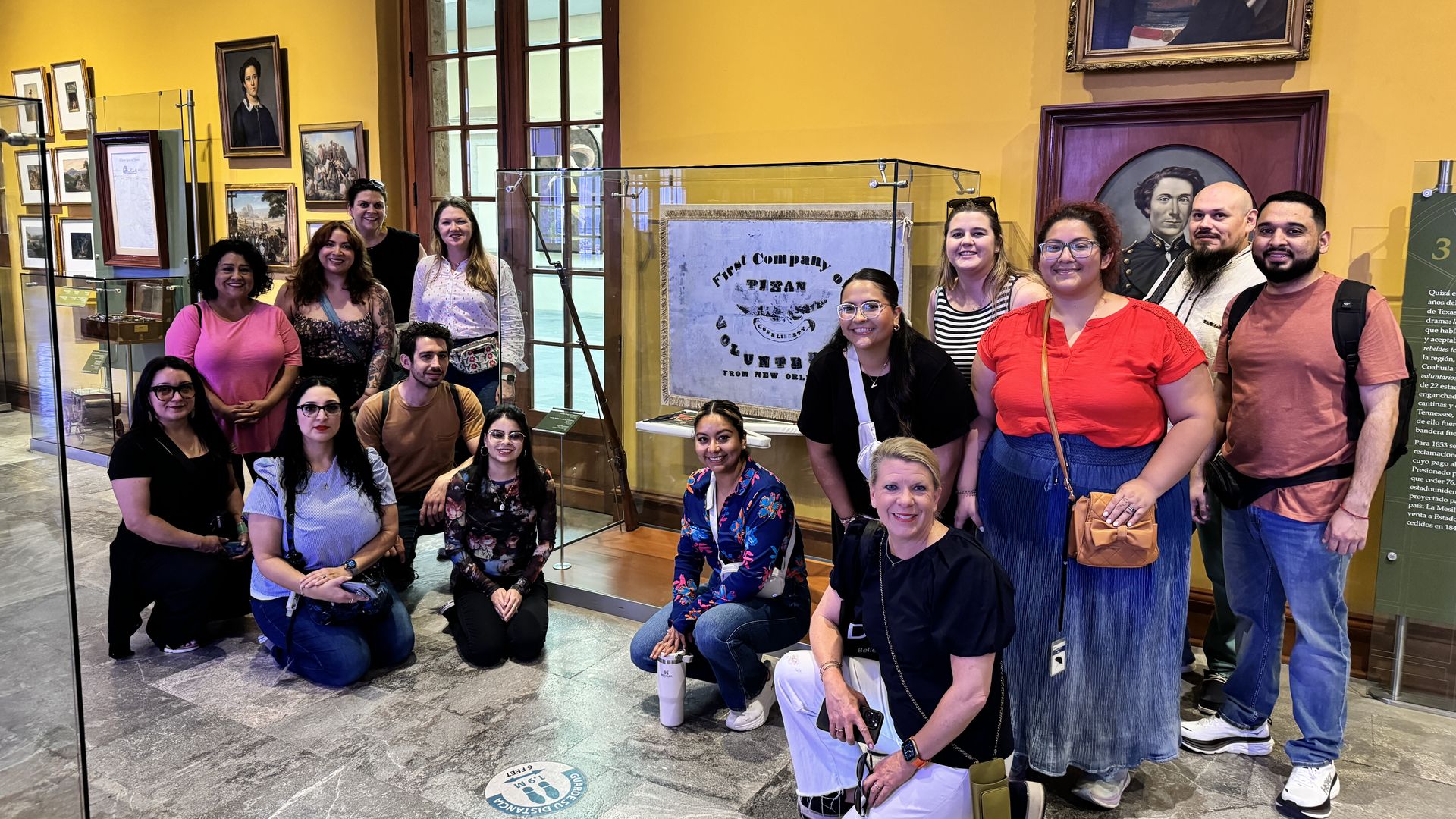 A group of people gather around a flag in a case. 