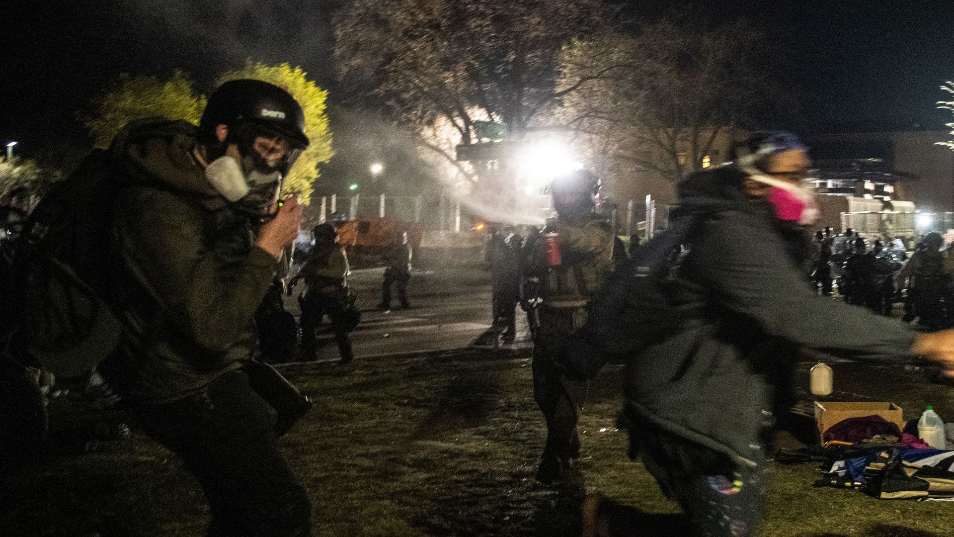 Law enforcement officers pepper spray freelance photographer Tim Evans (L) as he identifies himself a working journalist outside the Brooklyn Center police station
