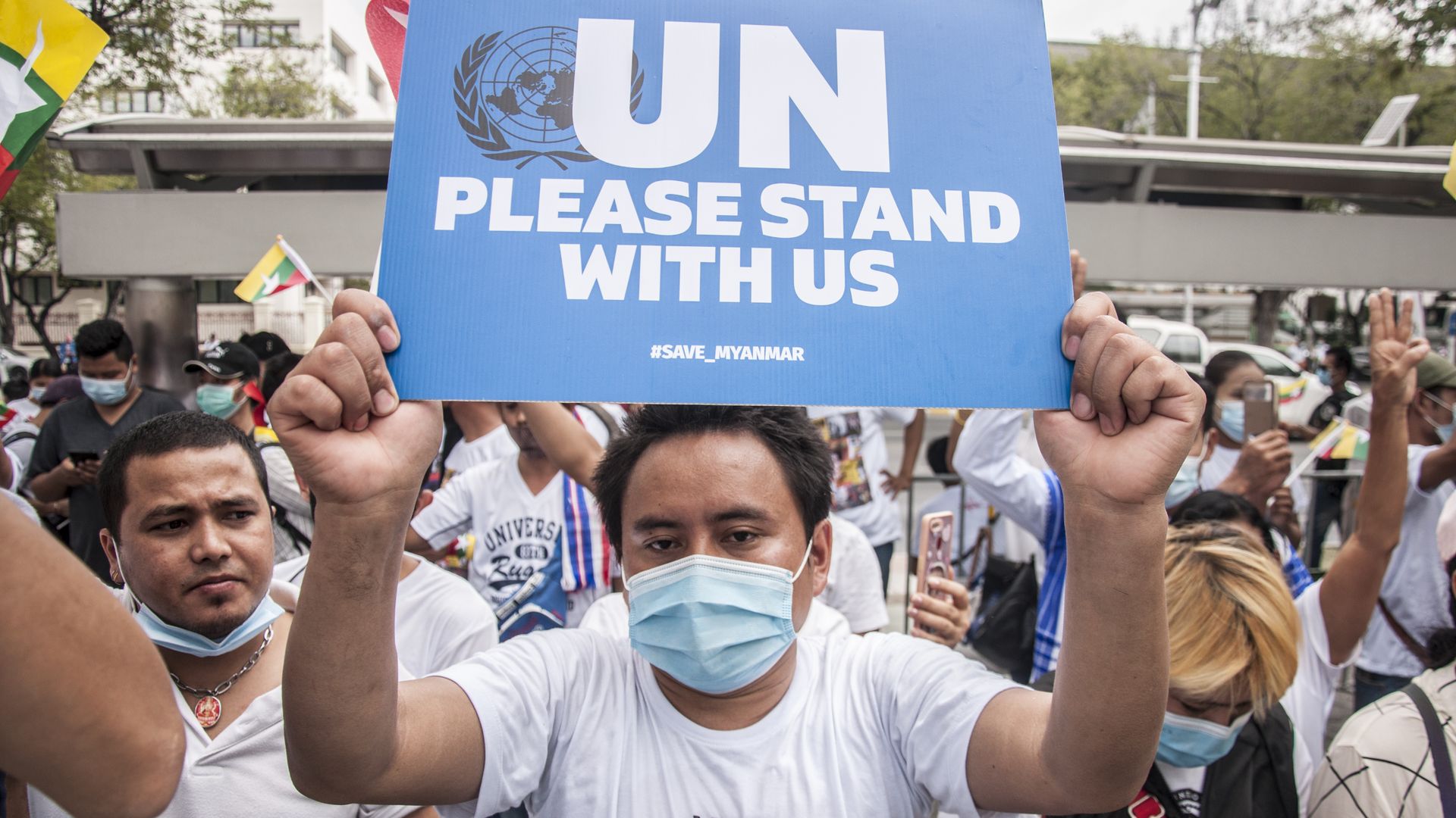 Picture of a Myanmar protester holding a placard that says "United Nations, please stand with us"