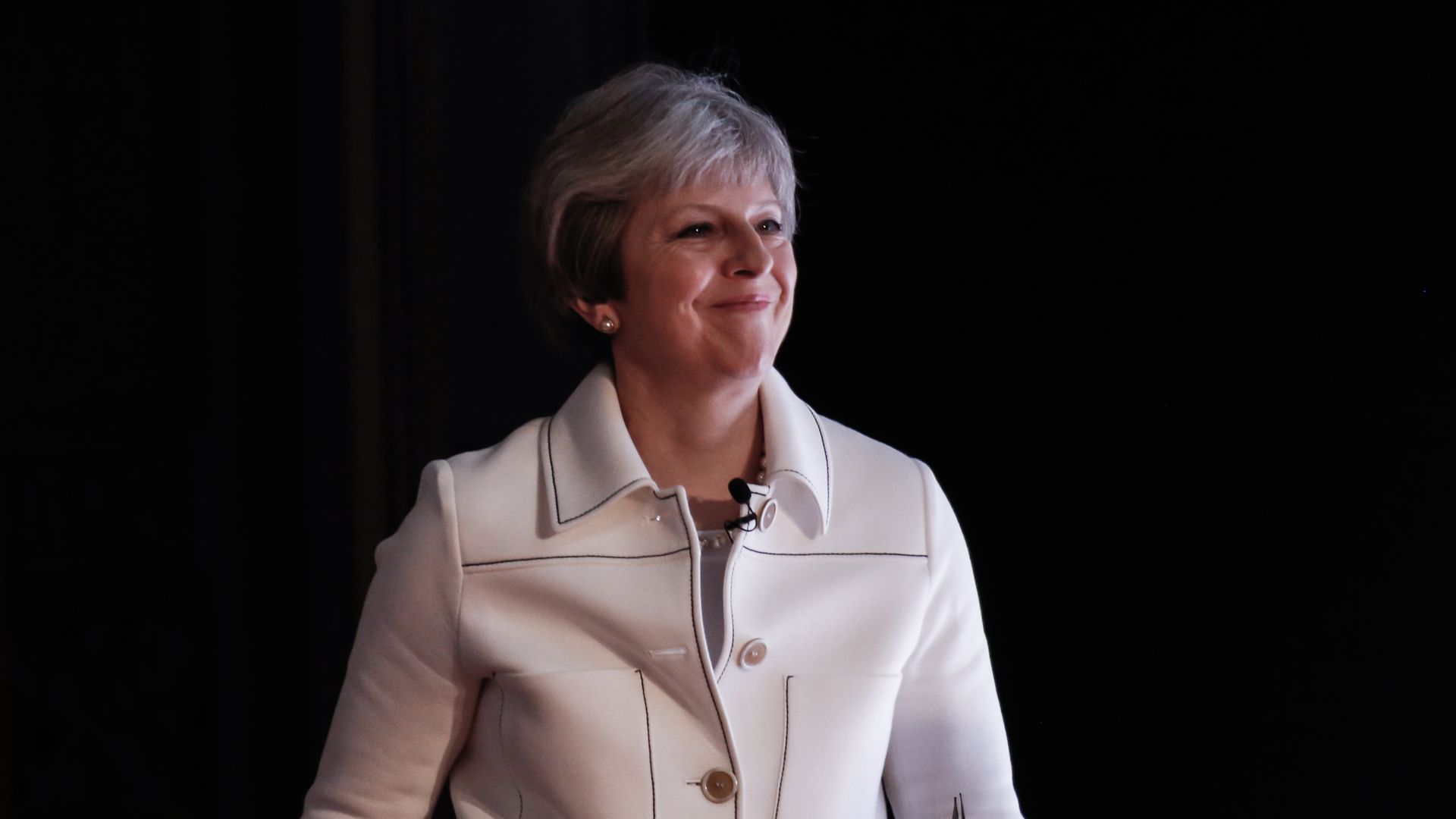 Theresa May on a black backdrop.