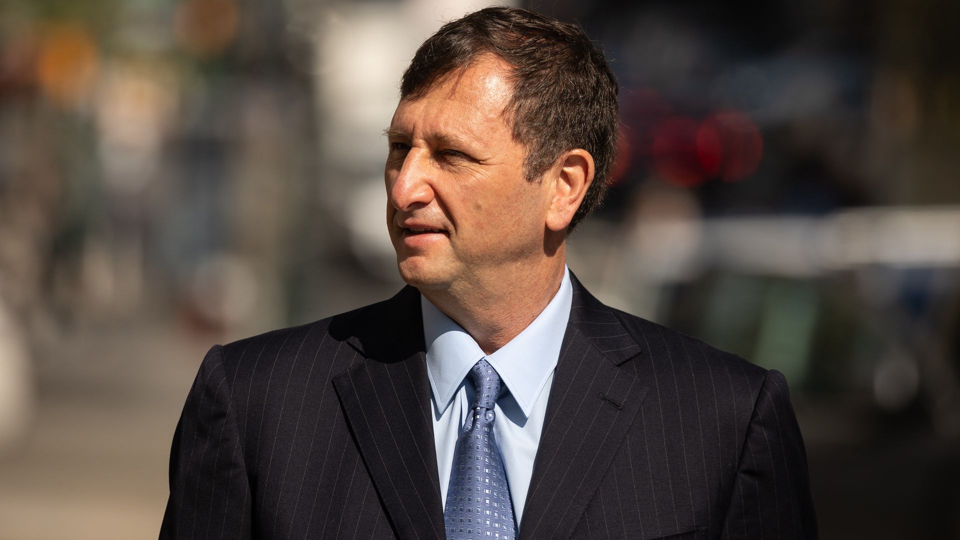 A middle-aged man in a dark suit and blue-grey tie. 