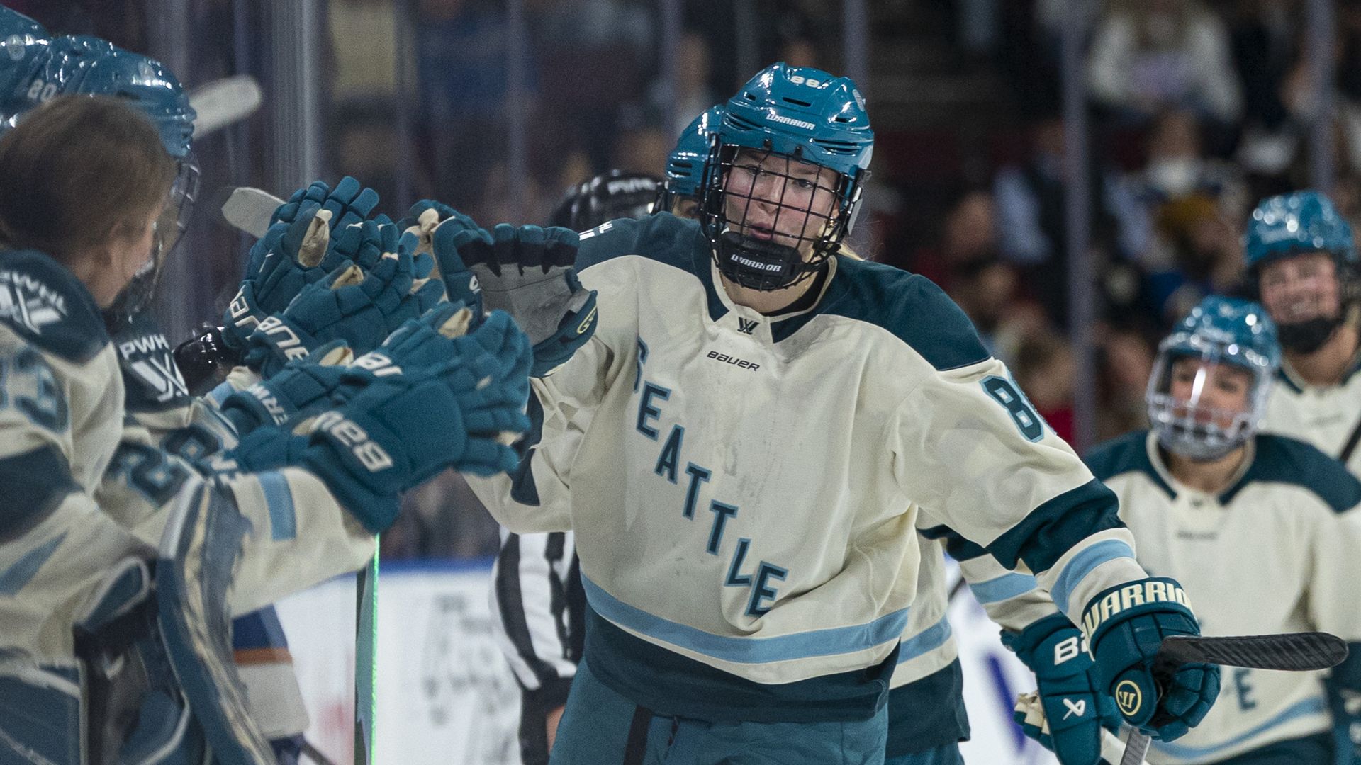 A Seattle Torrent hockey player bumps fists with her teammates on the bench after a goal. 