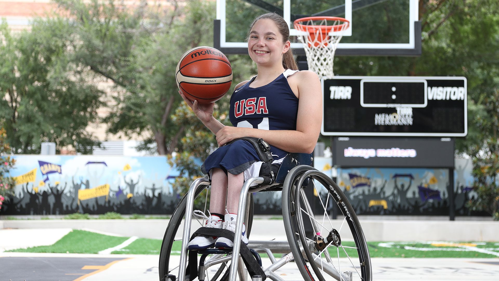 Photo of Kaitlyn Eaton, holding a basketball in a wheelchair.