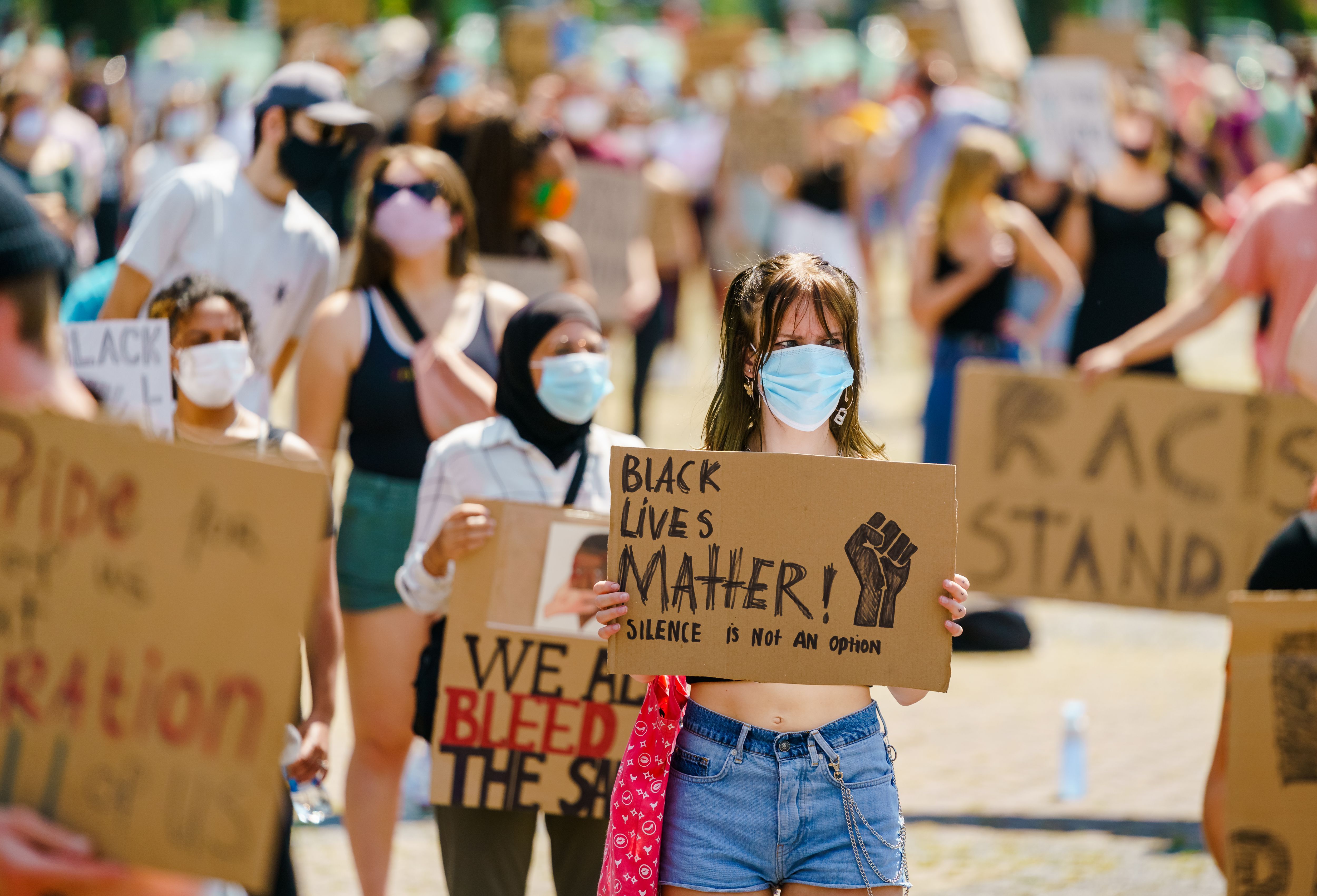 Two masked women hold signs that read "Black Lives Matter"