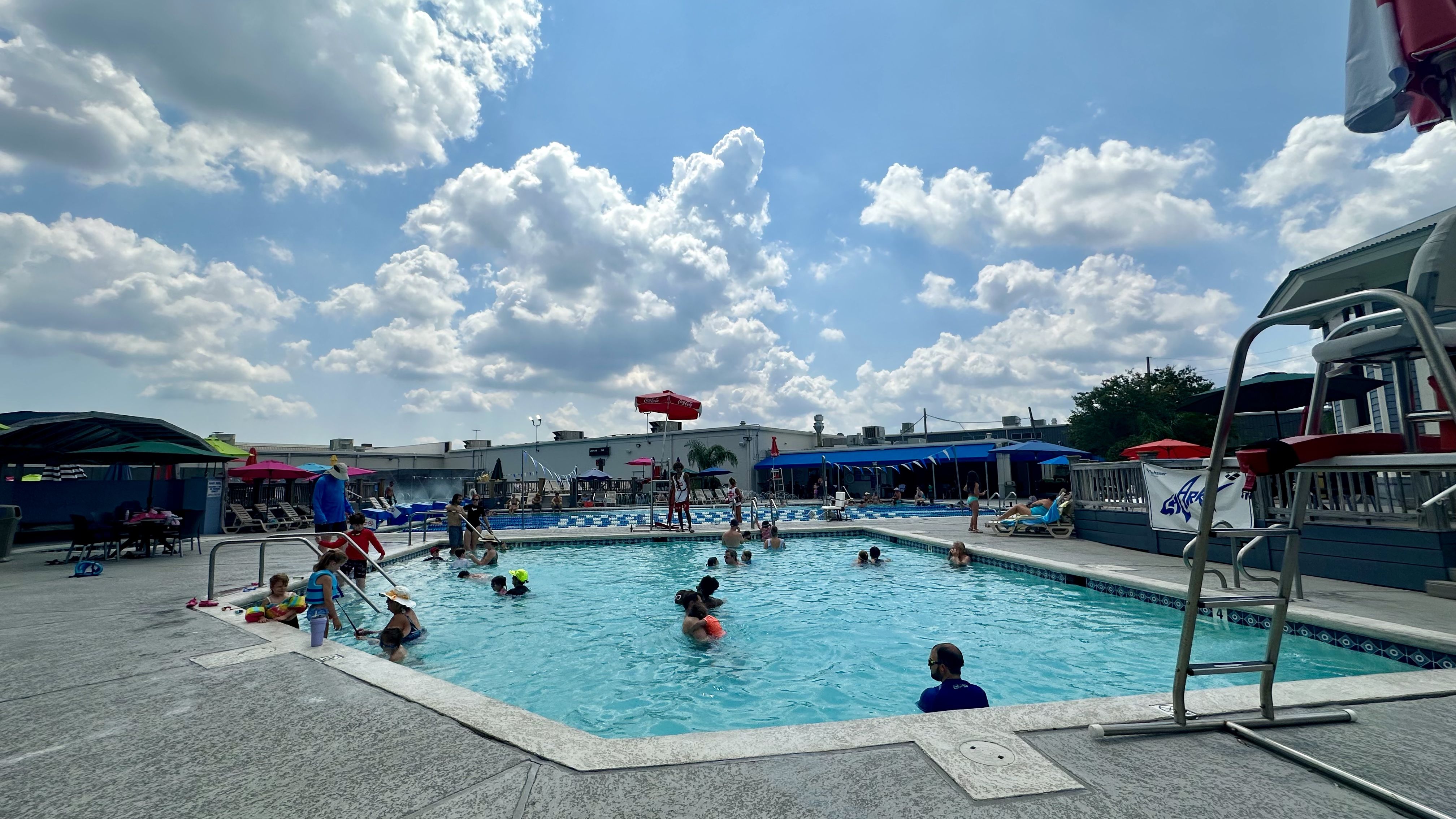 Photo shows a pool with people swimming