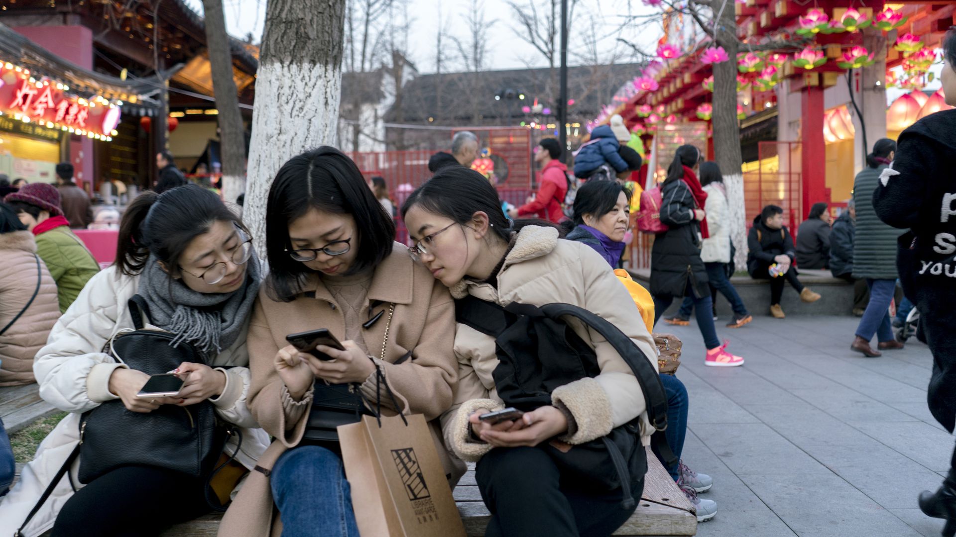 Chinese tourists on the side of a curb looking at cell phones