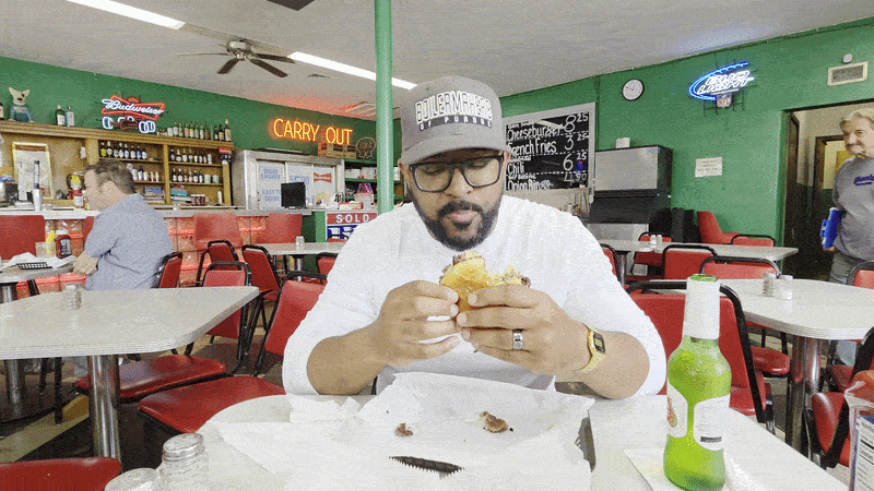 Axios reporter Justin Mack taking a bite of a burger at The Workingman's Friend in Indianapolis.