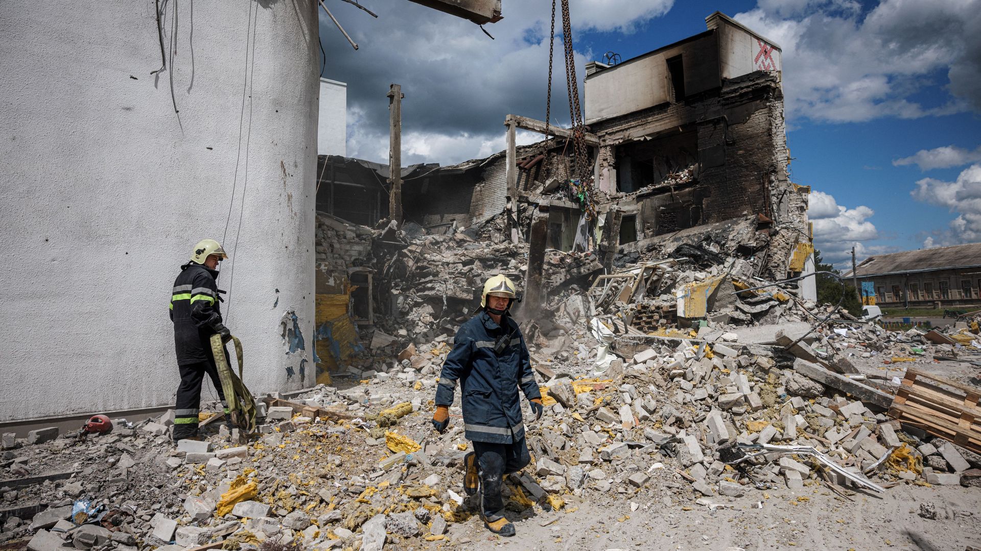 Firefighters clear rubble at a destroyed cultural centre, used as a humanitarian aid centre, hit by an airstrike on May 12, in Derhachi, near Kharkiv, on May 18, 2022, 