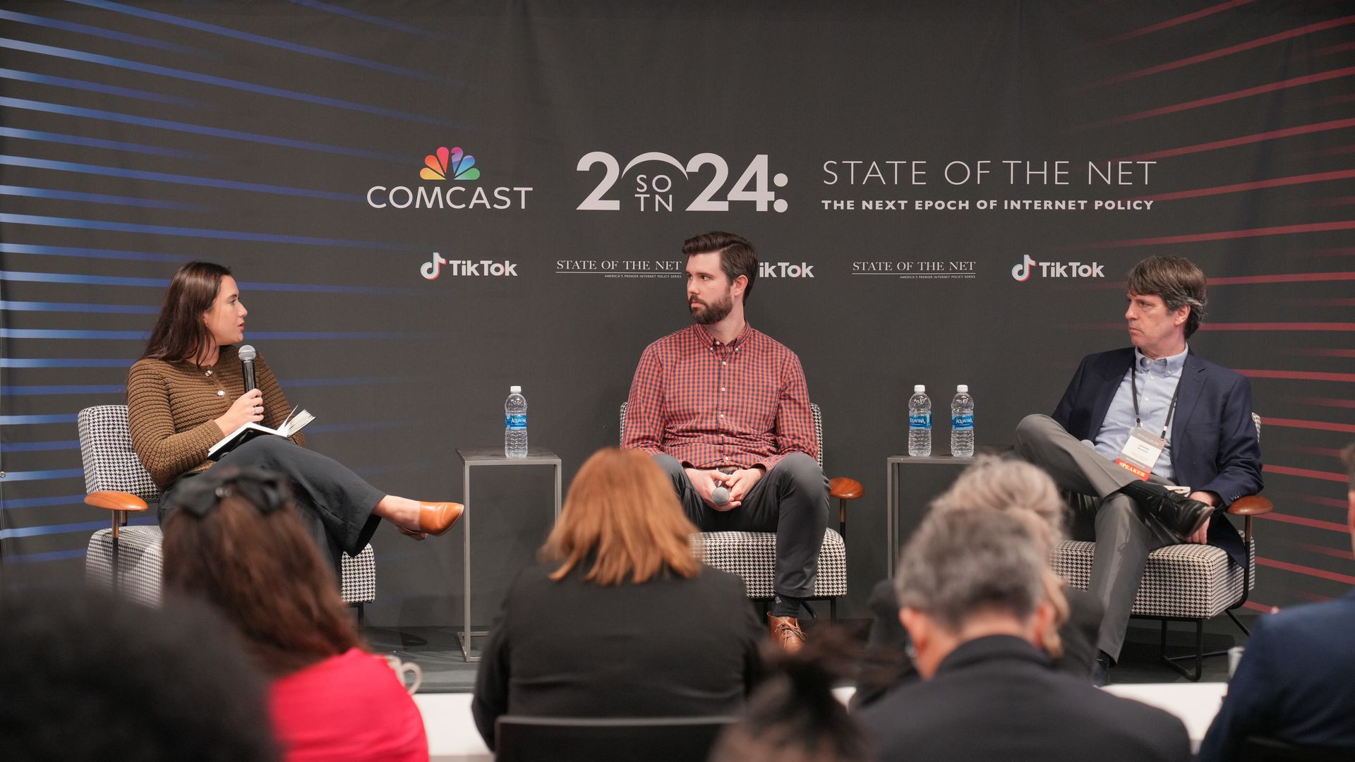 Three people seated on chairs on a stage