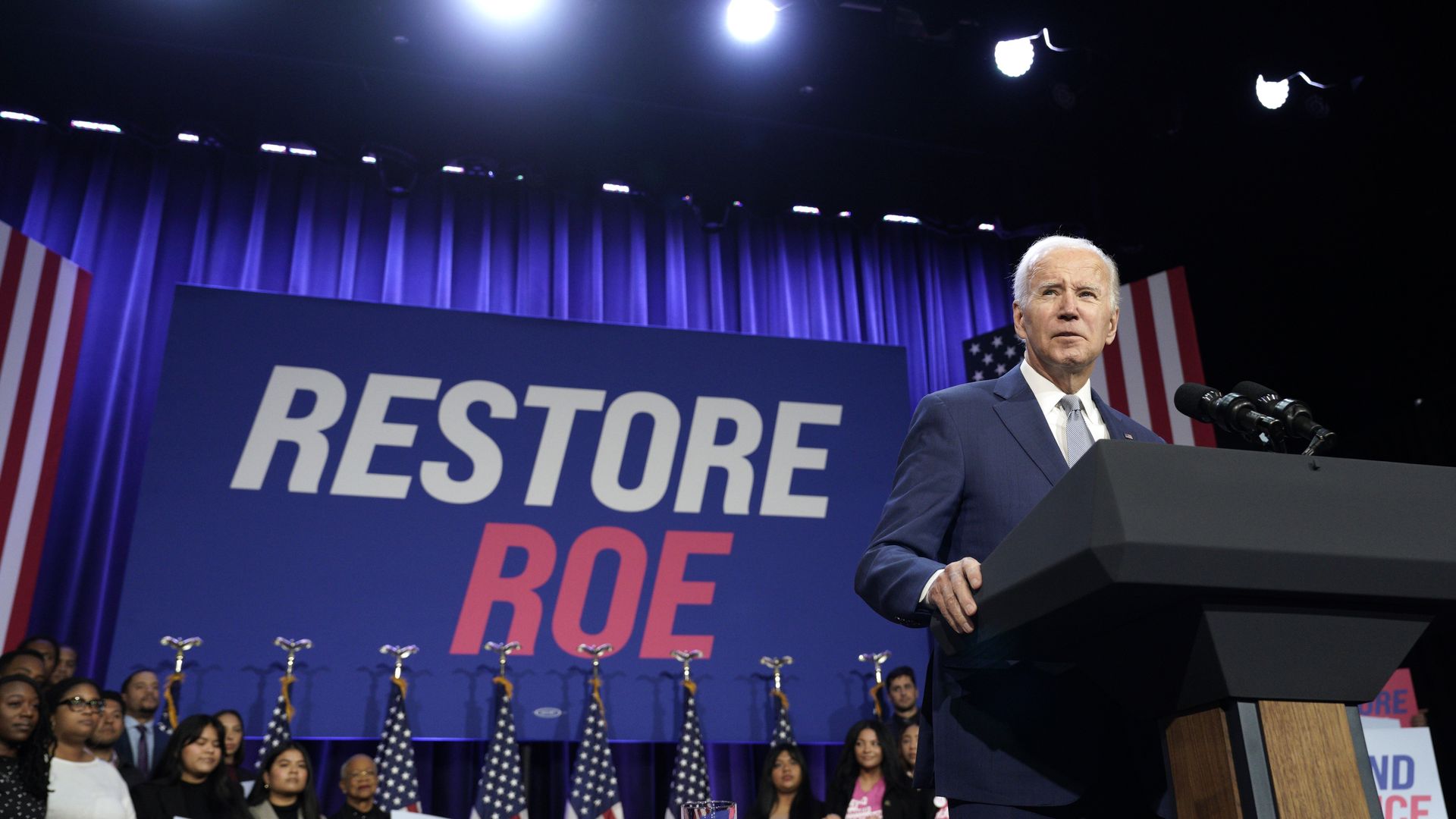Joe Biden standing in front of a backdrop that says "Restore Roe"