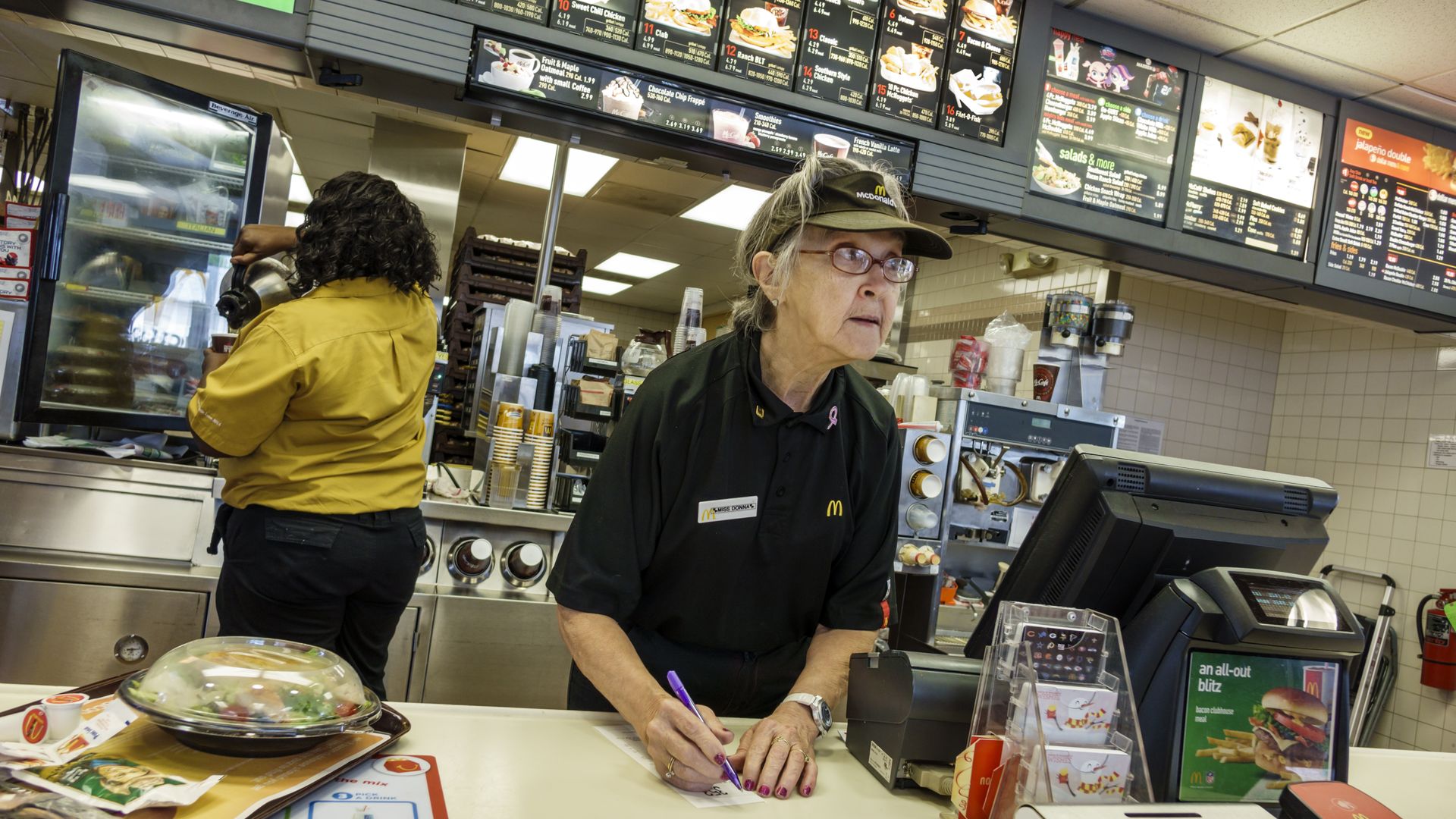 Senior woman working in McDonald's fast food restaurant. 