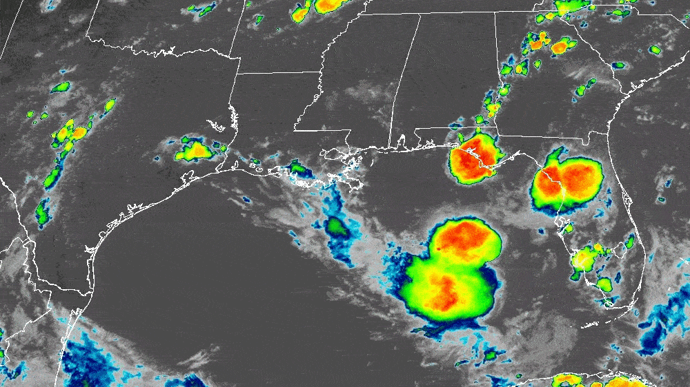 Color-enhanced satellite image showing storm clouds with red, orange, and green areas over the Gulf of Mexico, southern US states including Texas, Louisiana, Mississippi, Alabama, and Florida.