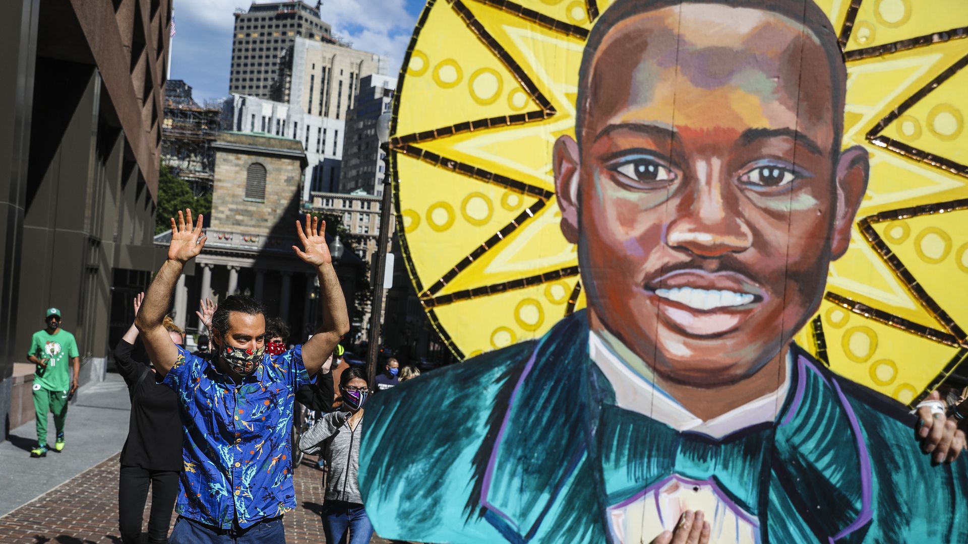 Protesters march in Boston as one holds up a painting of Ahmaud Arbery 