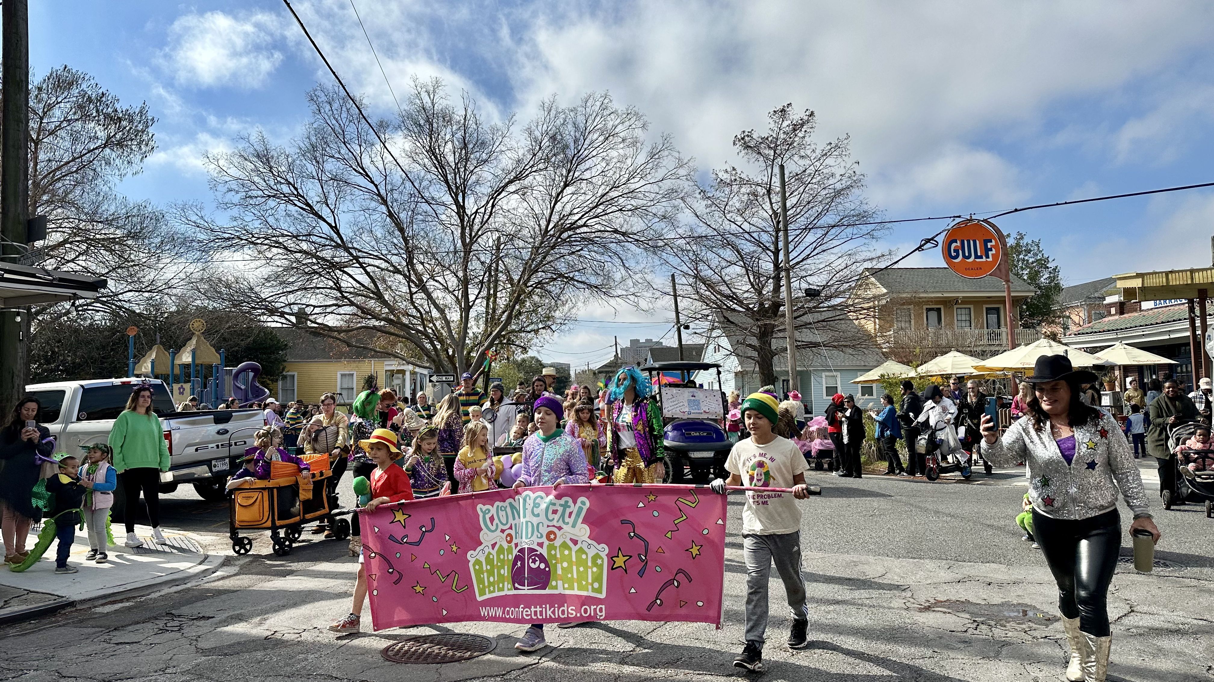 Photo shows children in costume walking in the Krewe of Confetti Kids parade in Algiers Point in New Orleans.