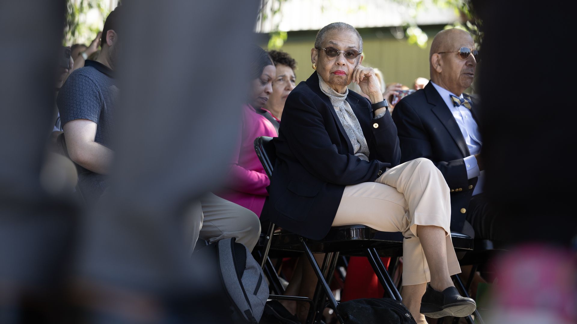 Eleanor Holmes Norton, wearing a black blazer and khaki pants, sits in a seat at an event.