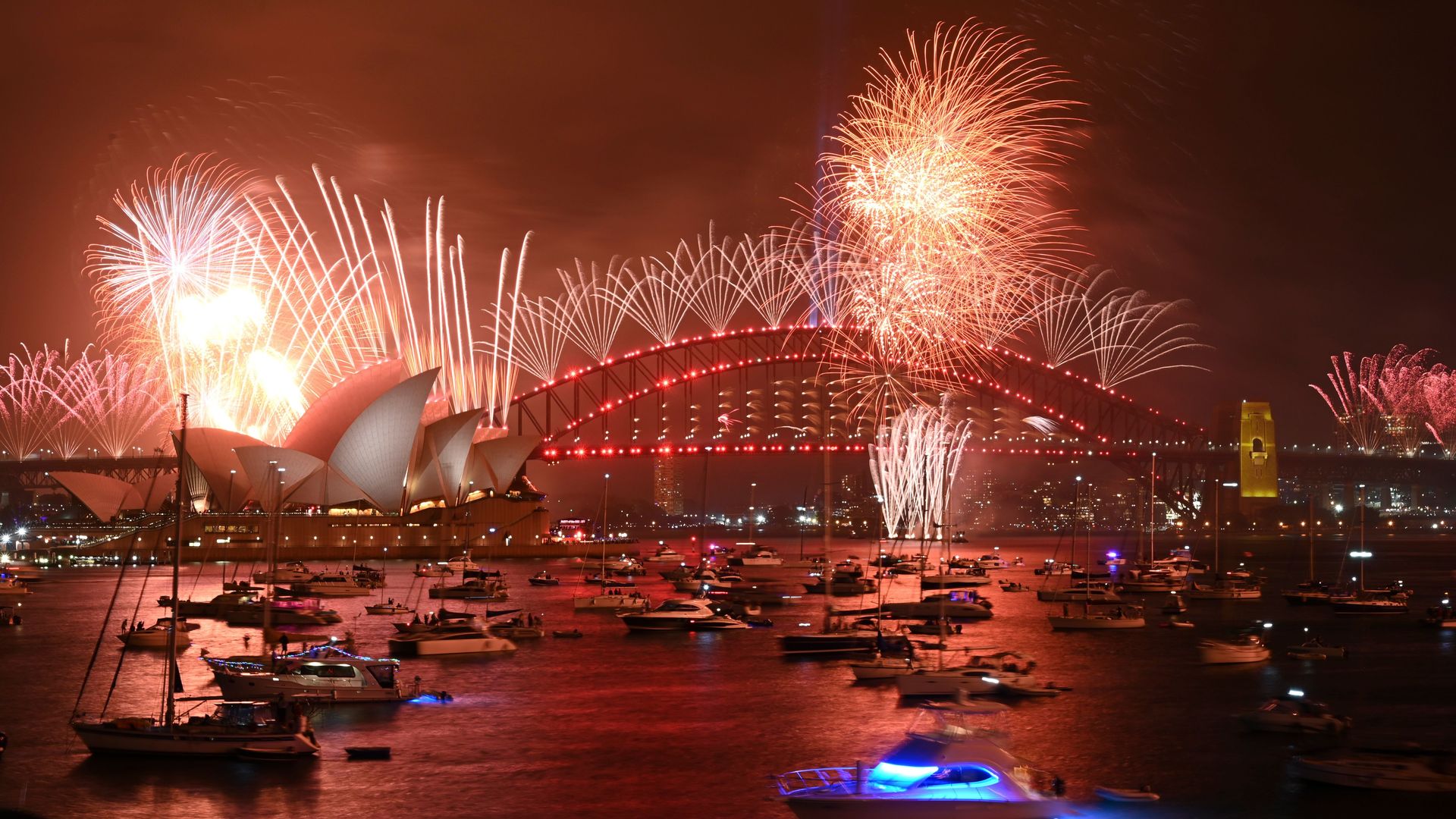 New Year's Eve fireworks erupt over Sydney's iconic Harbour Bridge and Opera House (L) during the fireworks show on January 1, 2020.