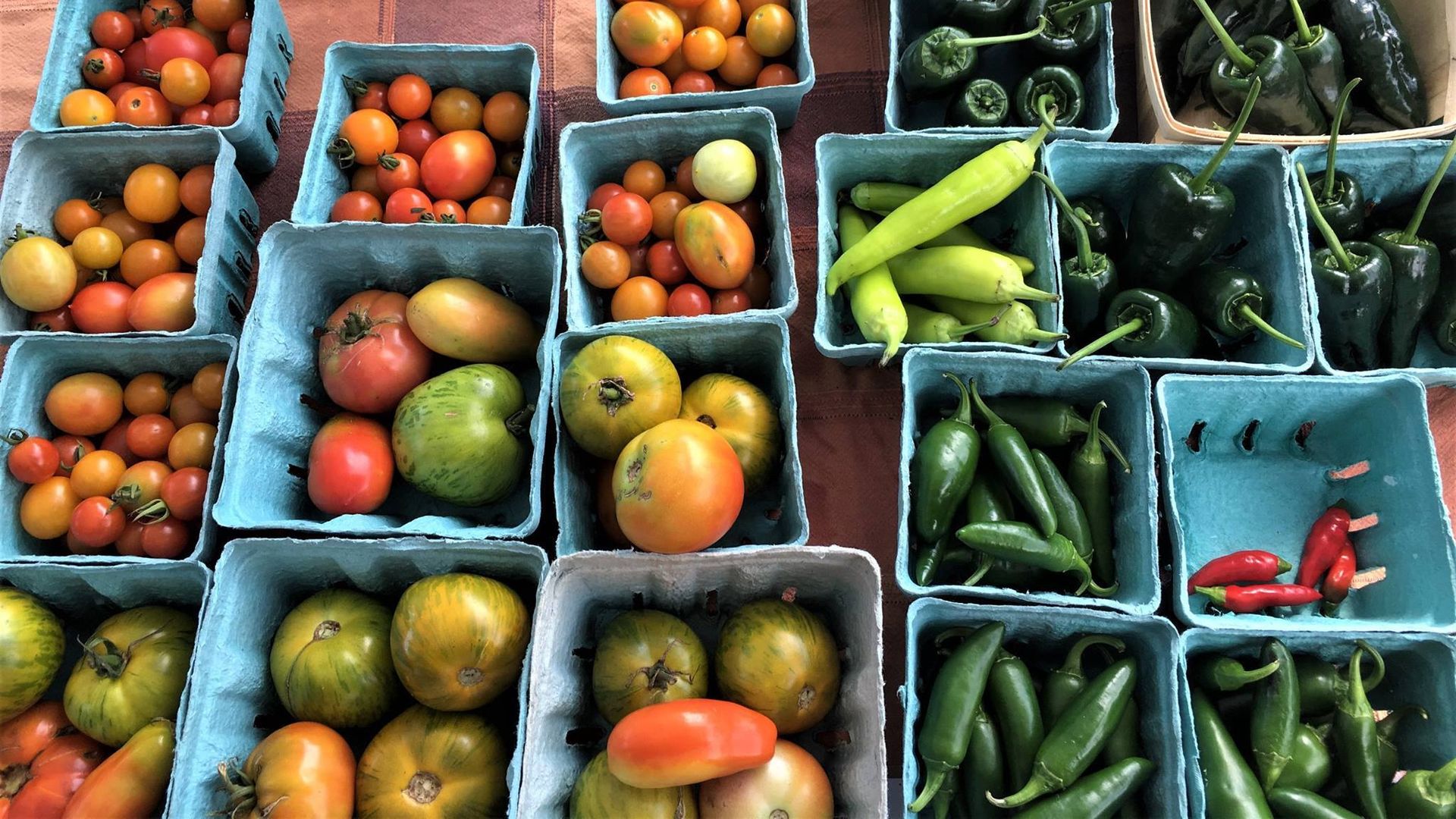 Various fruits and vegetables in cartons at a farmers market. 