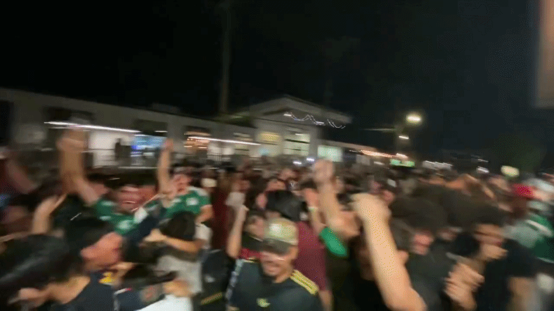 a video of a big crowd jumping and celebrating outside of a restaurant