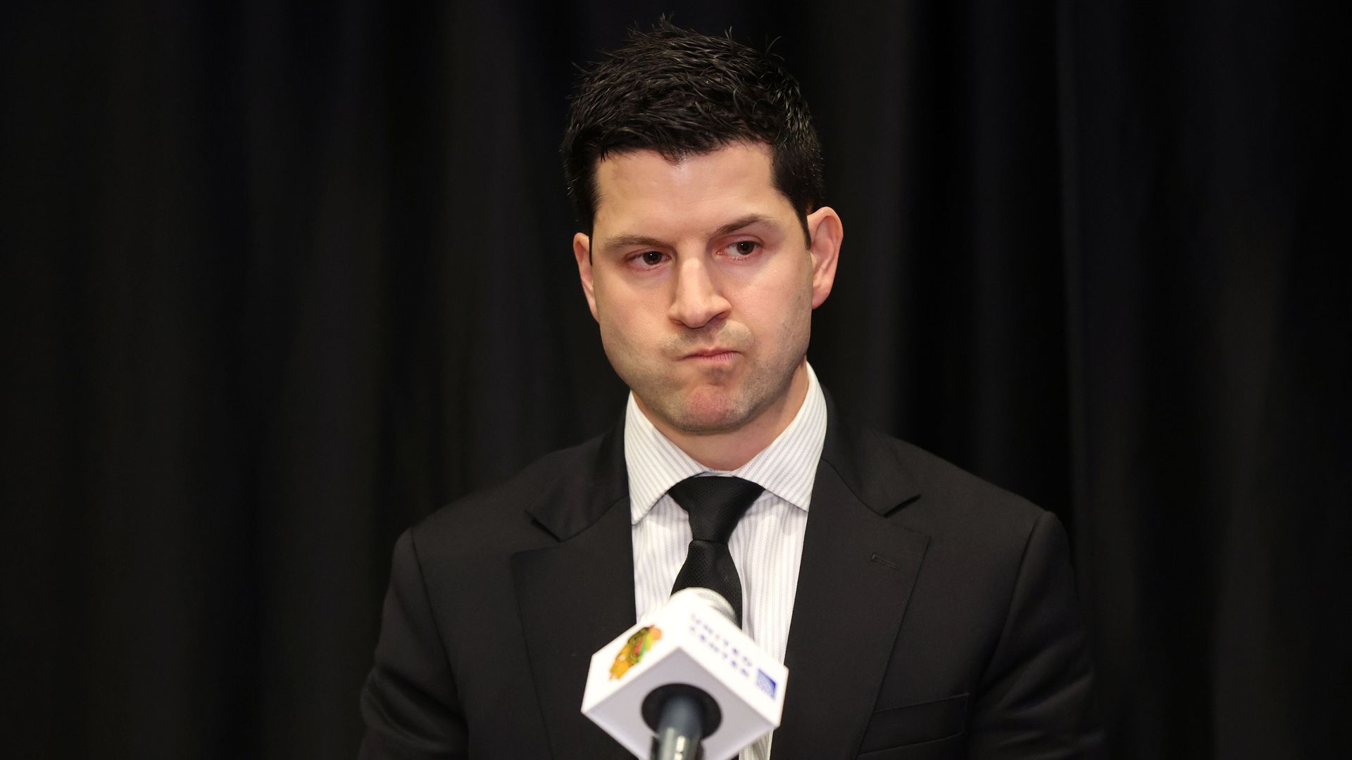 Photo of a man behind a podium listening to questions.