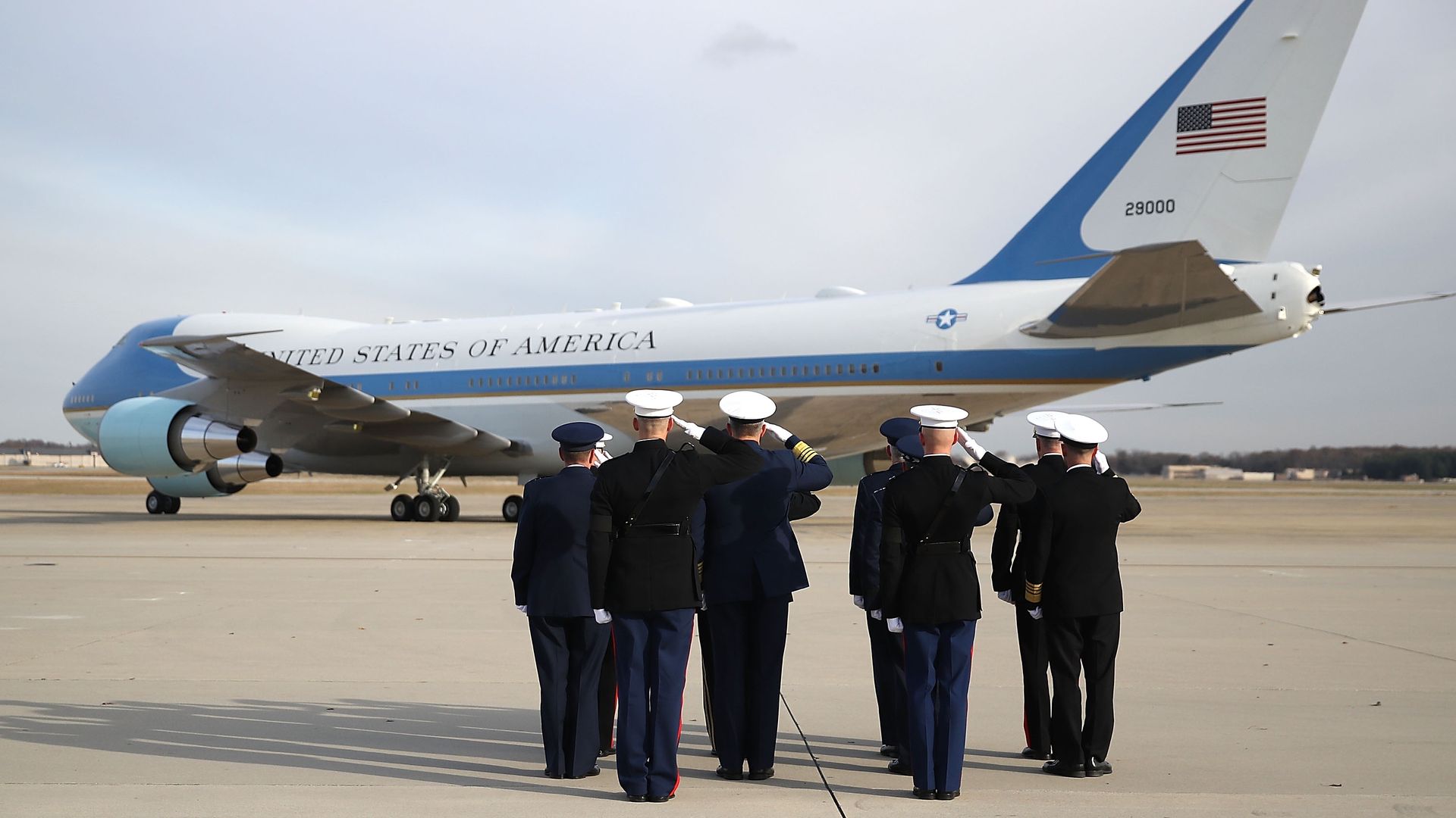 Troops salute Air Force One with George H. W. Bush casket on it.