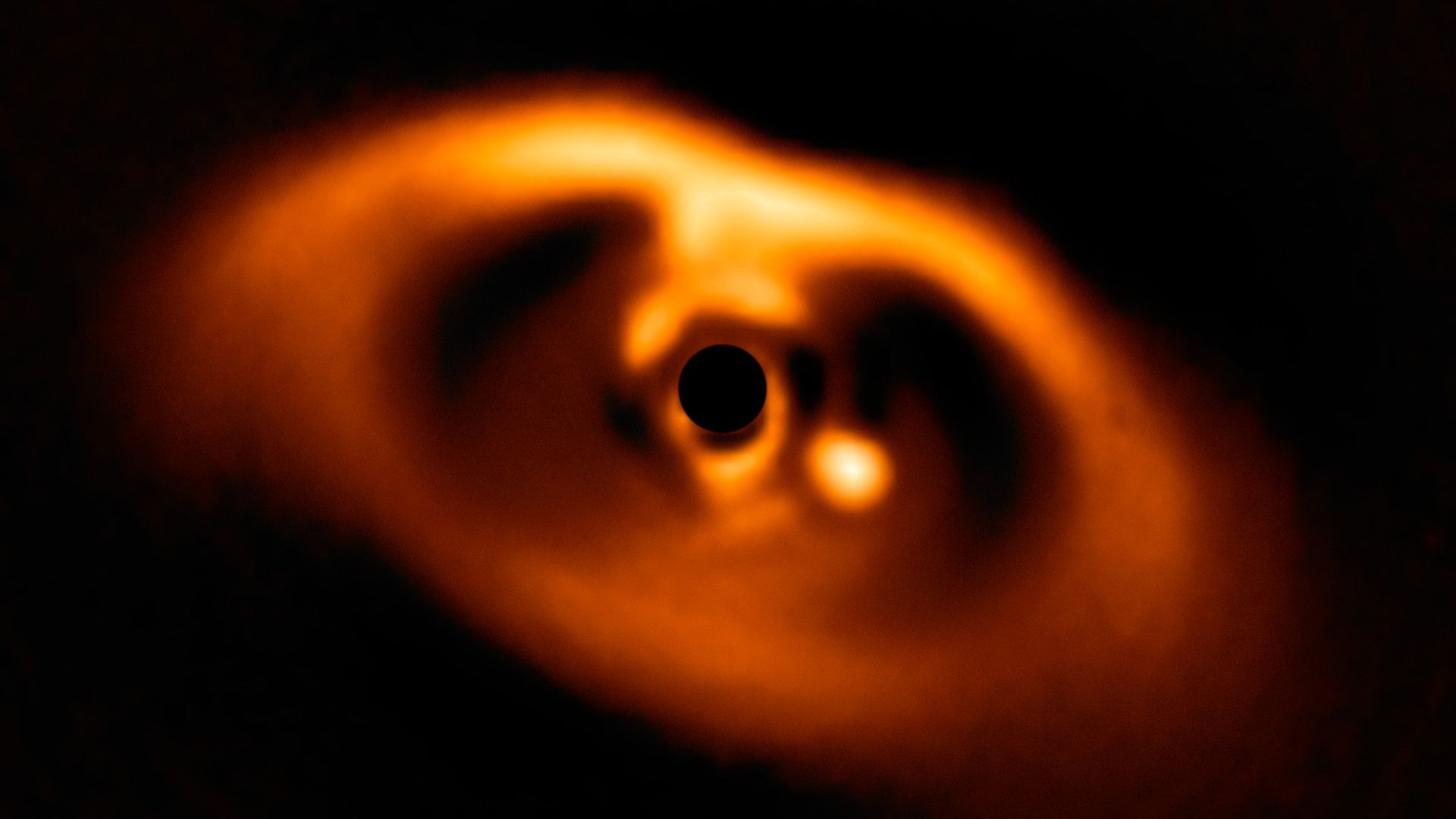 Image of a circumstellar disk with a bright spot showing a planet being born.