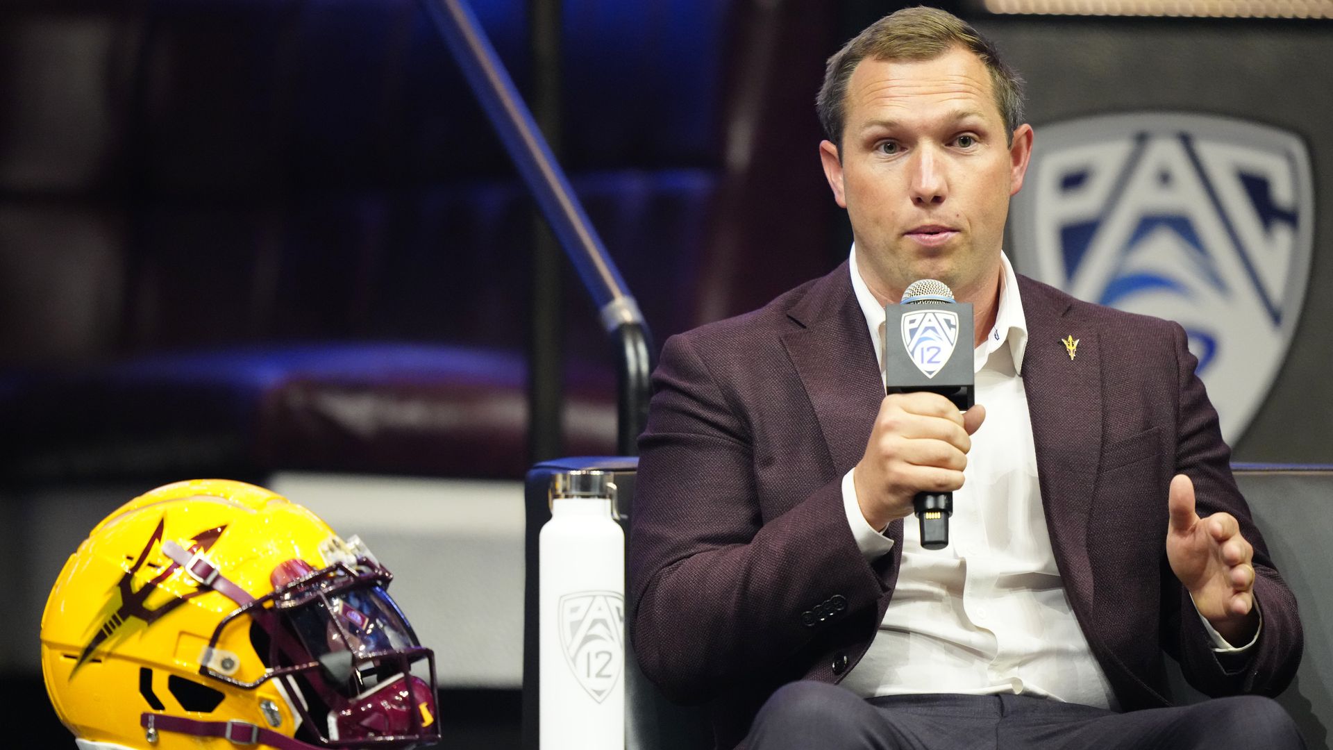 A man sitting next to an ASU helmet. 