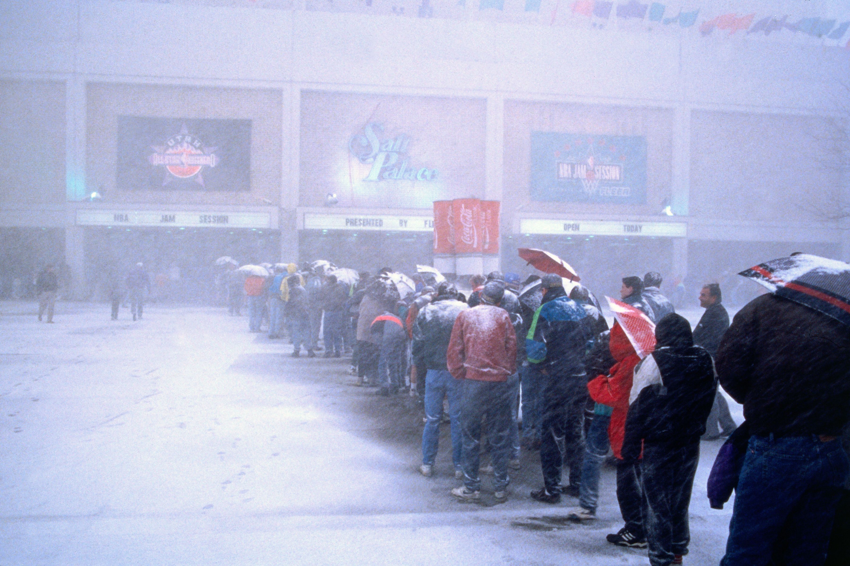 People wait outside in a long line to get into a venue during a blizzard.