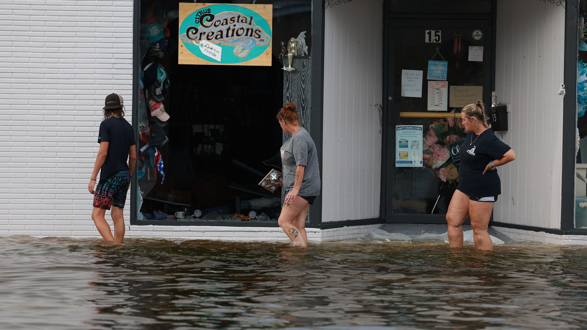 People walk in flood waters past a store that has a broken window after Hurricane Idalia passed offshore on August 30, 2023 in Crystal River, Florida. Hurricane Idalia hit the Big Bend area on the Gulf Coast of Florida as a Category 3 storm. 