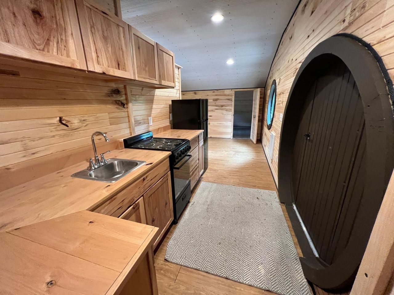 A kitchen with wood walls, cabinets and floor.
