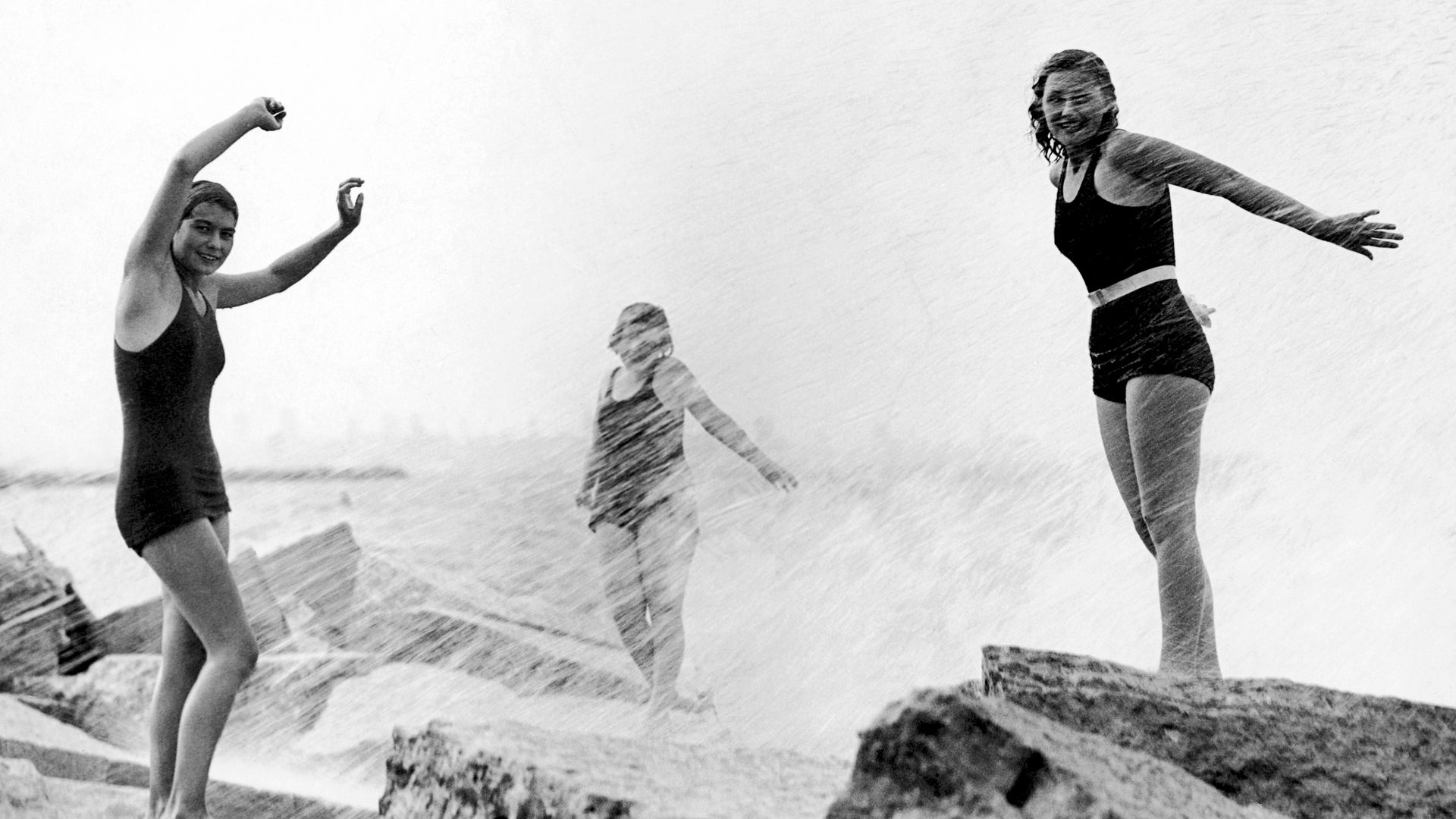 Photo of women swimming and standing on rocks in water 