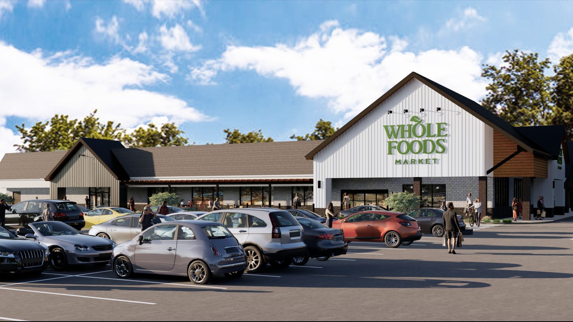 Parking lot full of cars with people walking toward a large Whole Foods Market store under a blue sky with scattered clouds and surrounded by trees.