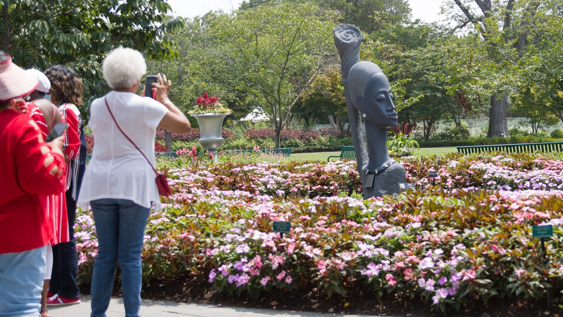 Ladies taking photos of a sculpture and flowers