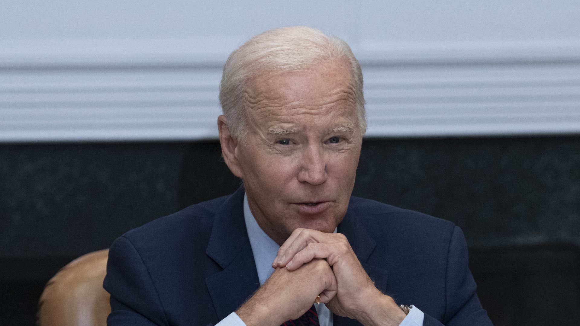 President Joe Biden resting his chin on his clasped hands.