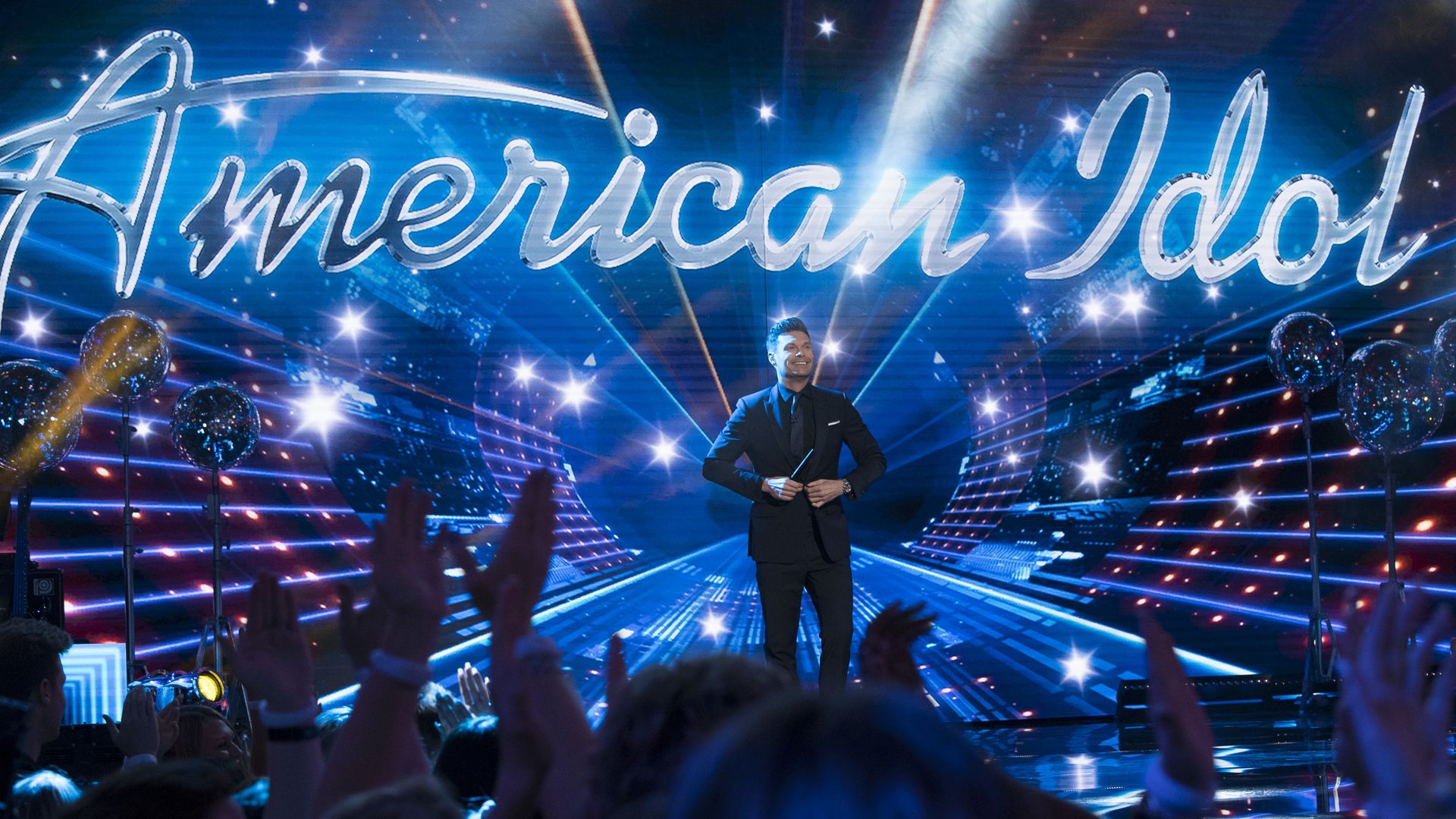 A photo of Ryan Seacrest in front of an American Idol sign