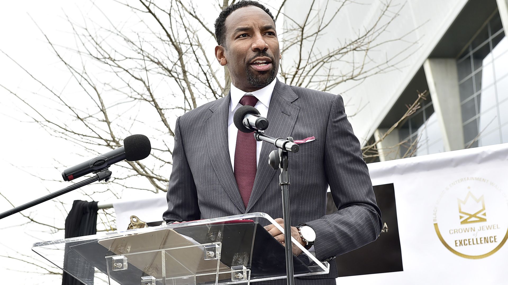 Andre Dickens wears a gray suit and speaks at a lectern