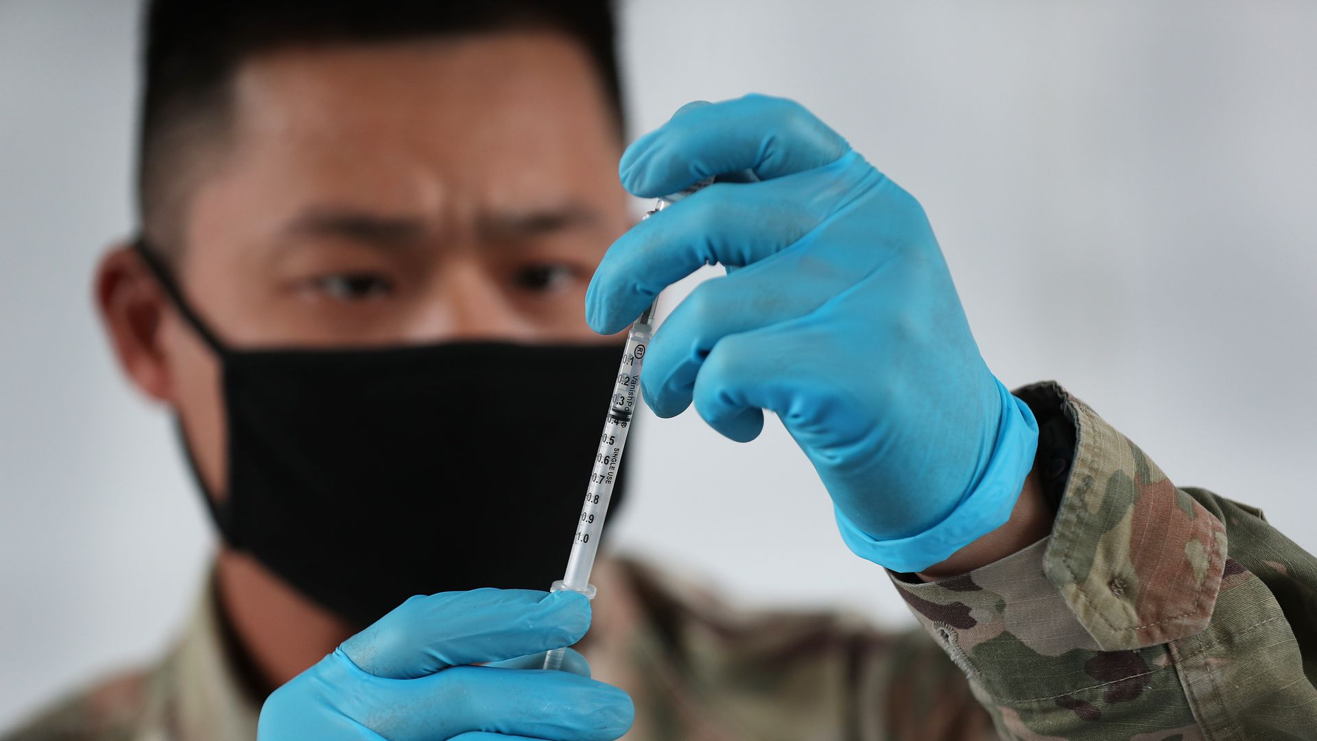  A U.S. Army soldier from the 2nd Armored Brigade Combat Team, 1st Infantry Division, prepares Pfizer COVID-19 vaccines to inoculate people at the Miami Dade College North Campus 