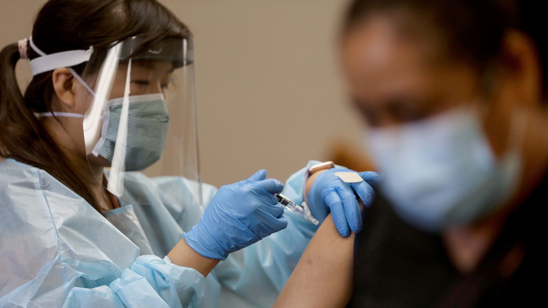 A woman administers a shot to a patient.