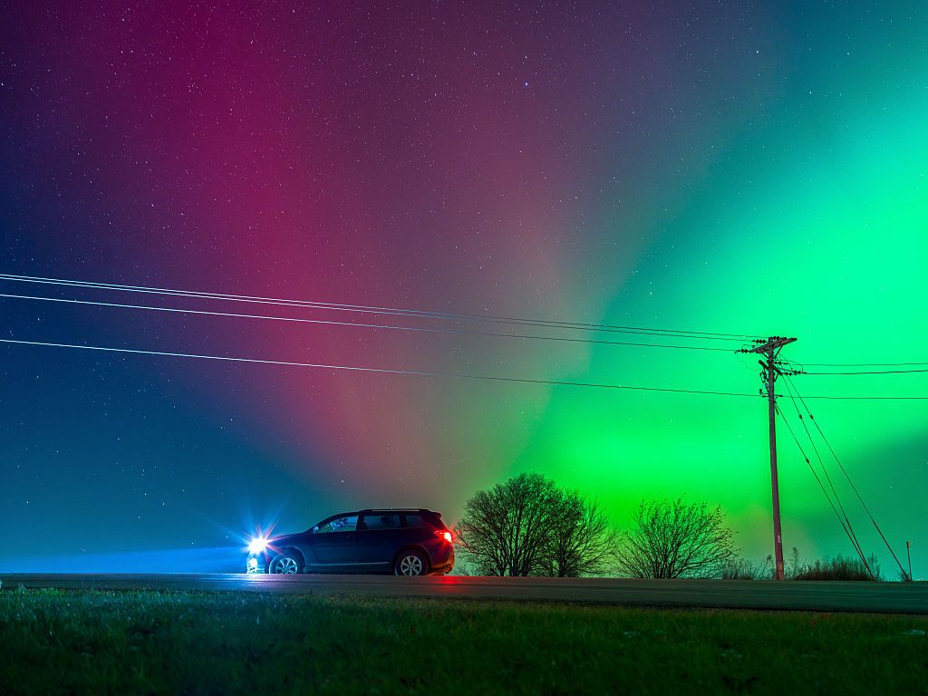 The Aurora Borealis lights up the night sky over Monroe, Wisconsin, on November 11, 2025, during one of the strongest solar storms in decades. The geomagnetic event pushes the northern lights deep into the continental United States, with vibrant pink, red, and green hues illuminating rural farmstead