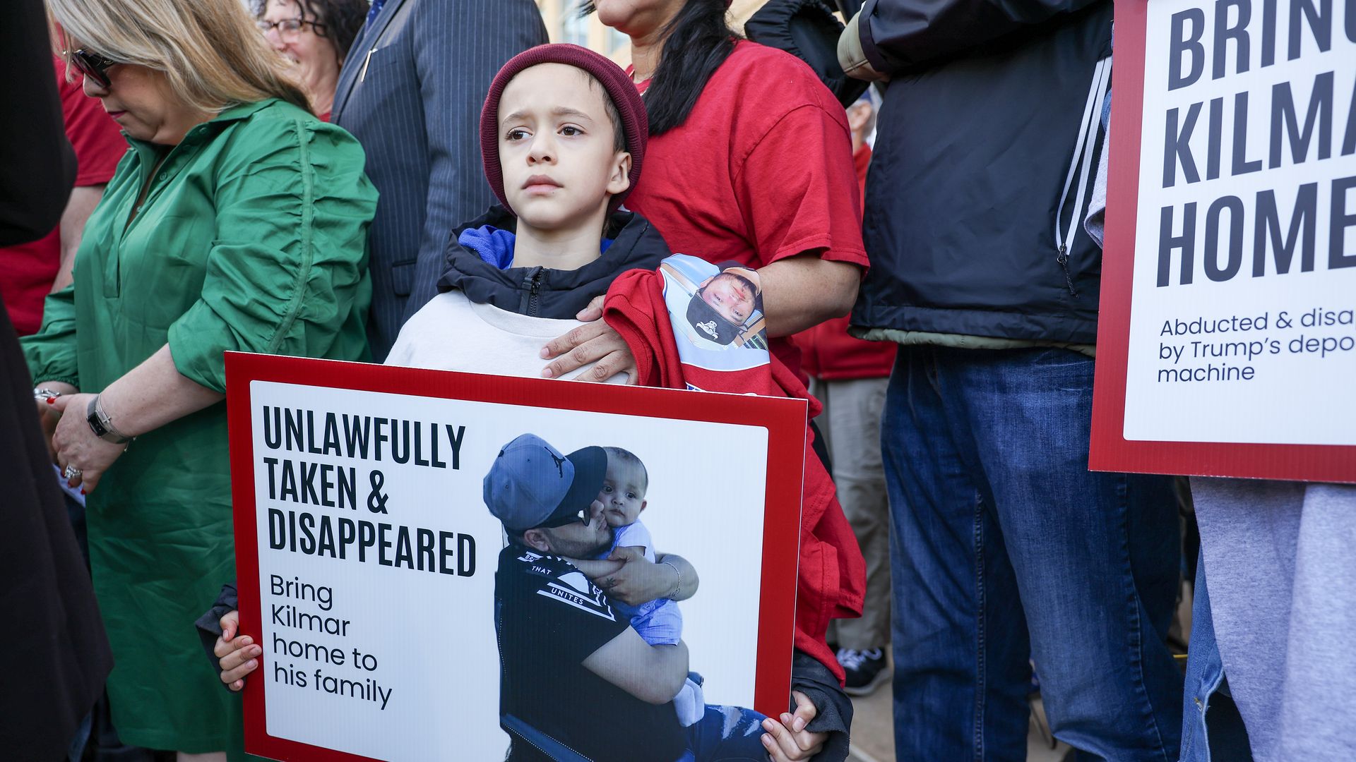 Child holds a sign that says "Unlawfully taken & Disappeared: Bring Kilmar home to his family" 