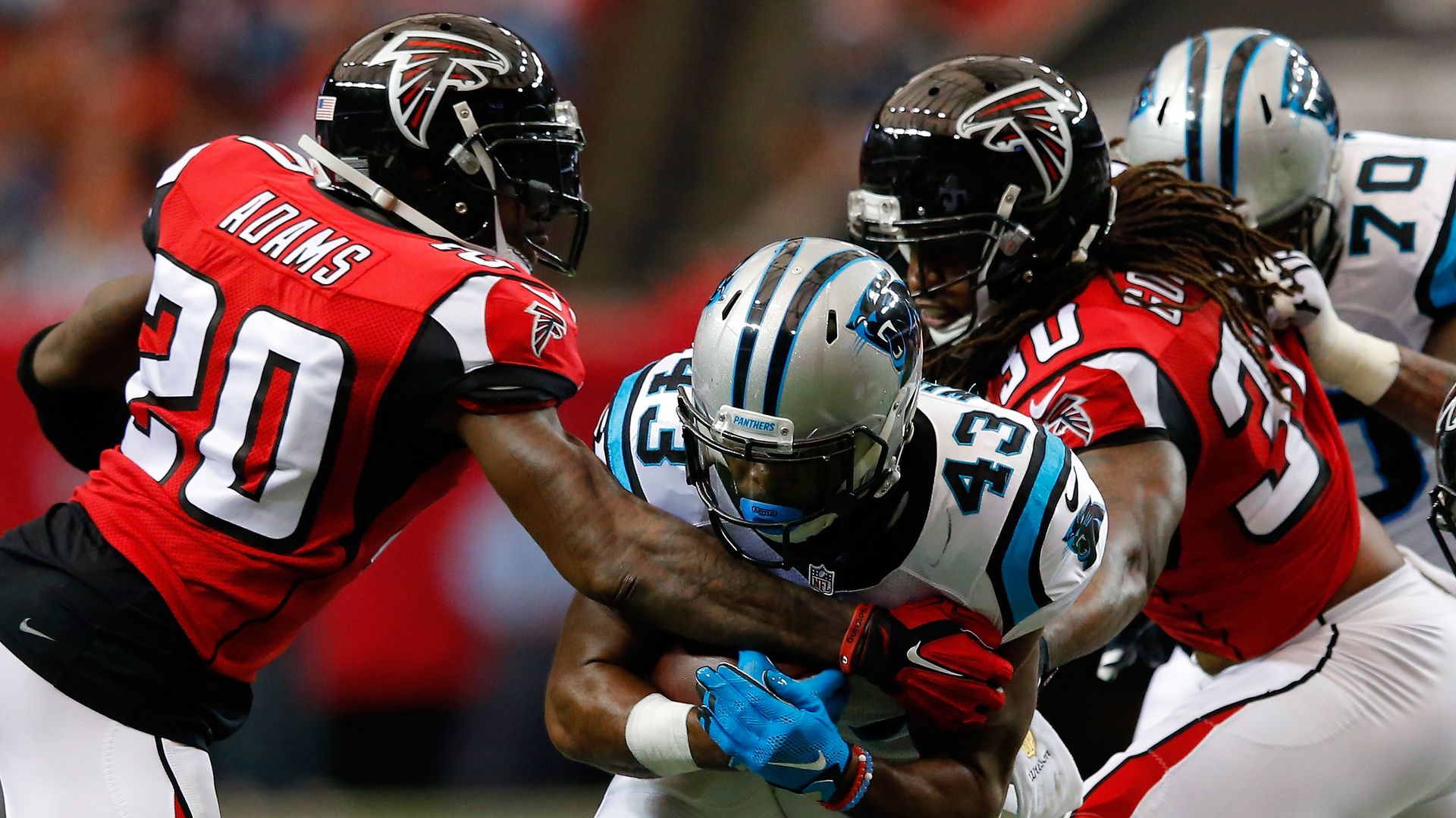 Fozzy Whittaker #43 of the Carolina Panthers runs the ball past Phillip Adams #20 and Charles Godfrey #30 of the Atlanta Falcons.