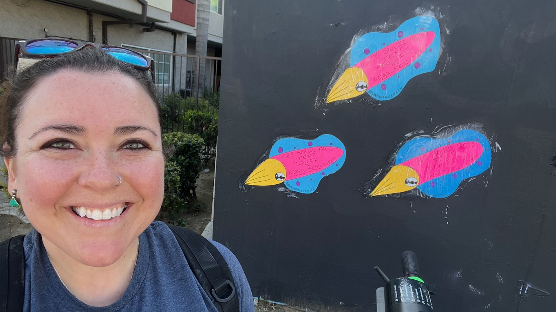 Philly squid biologist Sarah McAnulty standing next to three squid stickers.