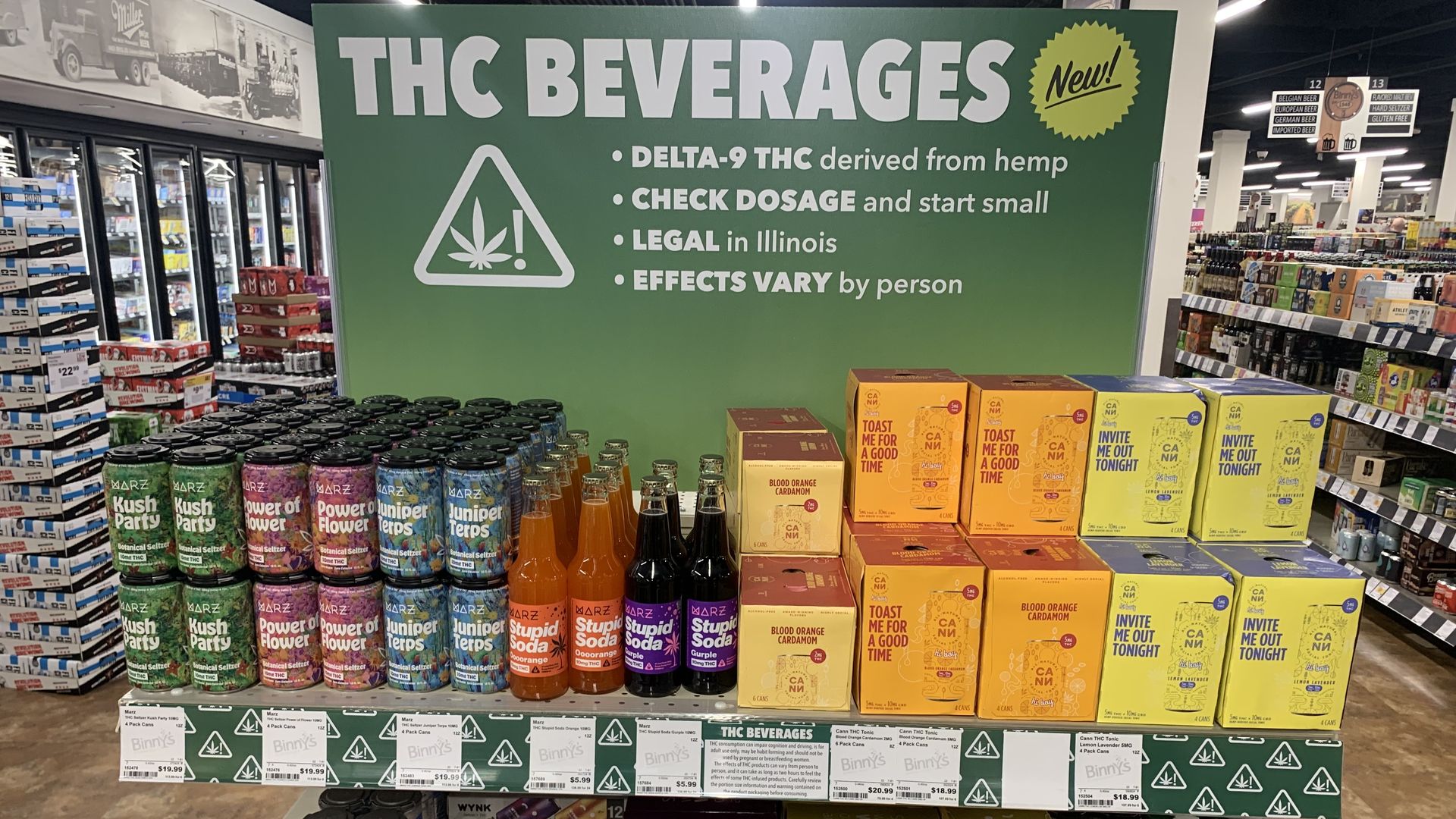 Display of colorful THC beverage cans and boxes with a green sign explaining they contain delta-9 THC, are legal in Illinois, dosage should be checked, and effects vary by person.