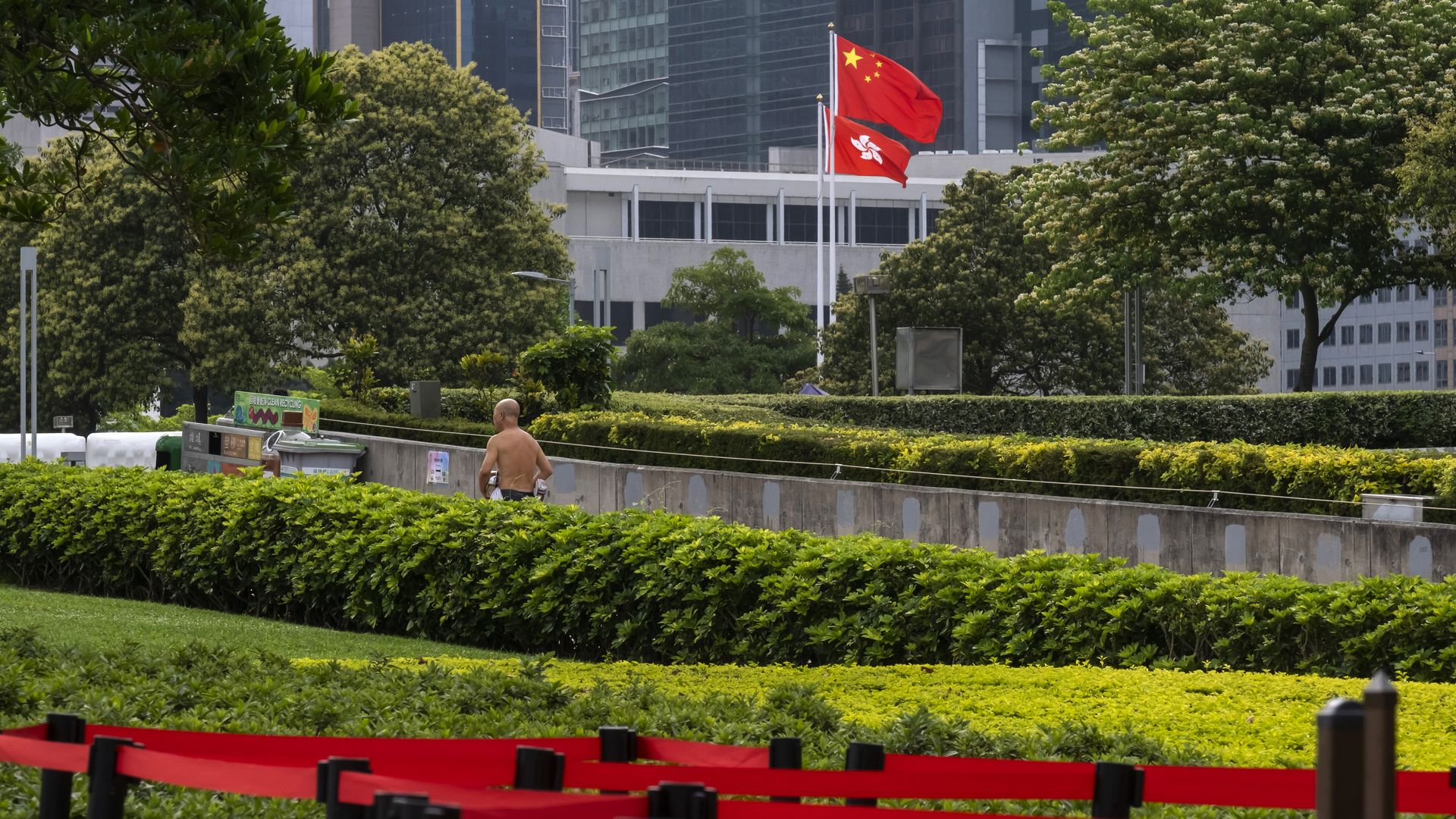 A person walks past the flags of China, top, and the Hong Kong Special Administrative Region (HKSAR) outside the Legislative Council building in Hong Kong, China, on Monday