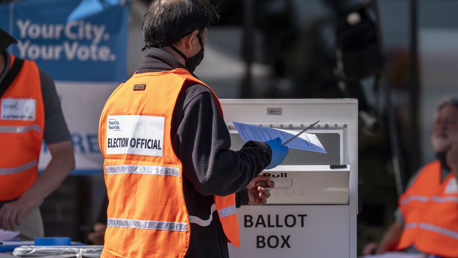 An election judge drops a ballot in a ballot box at a drive through drop-off for absentee ballots on August 11, 2020 in Minneapolis, Minnesota.